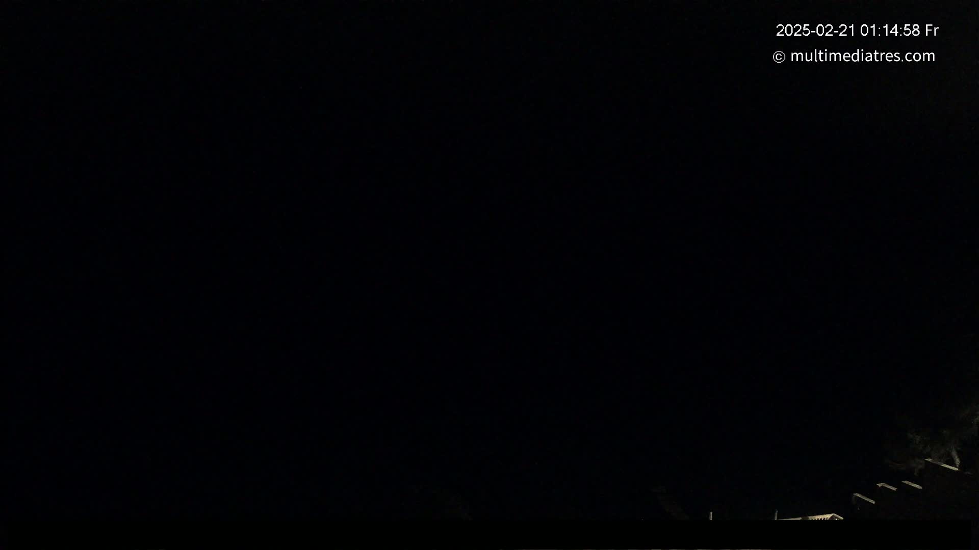 A nighttime outdoor scene shows a mostly dark sky with a few dimly lit structures visible at the bottom edge.