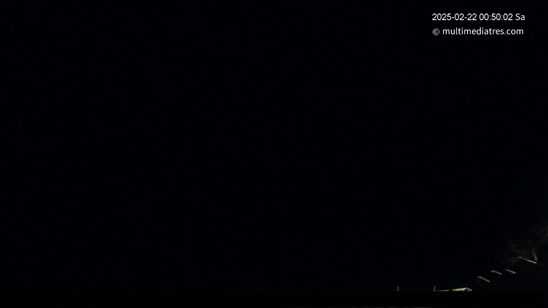 A nighttime image shows a mostly dark sky with a very faint suggestion of structures at the bottom.