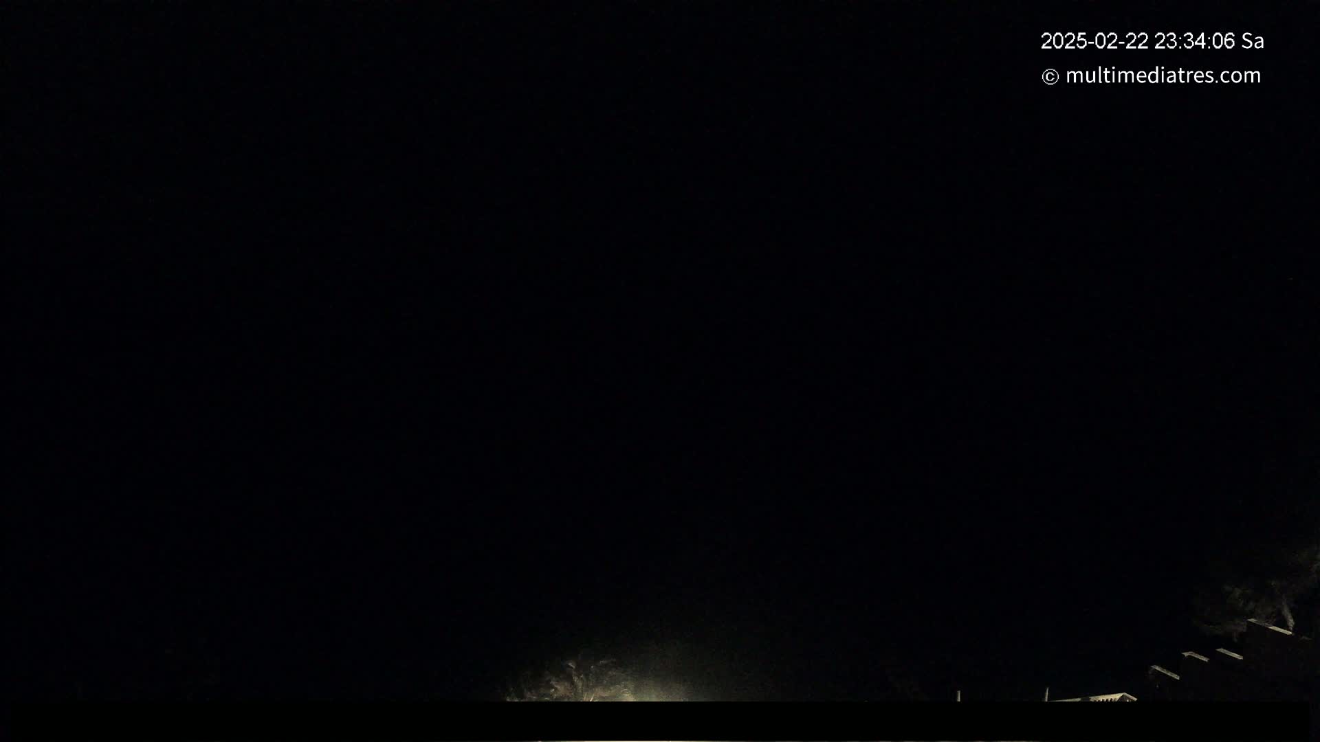 A dark, nighttime scene shows a faint glow near the bottom of the frame, possibly from distant lights, under a completely overcast sky.