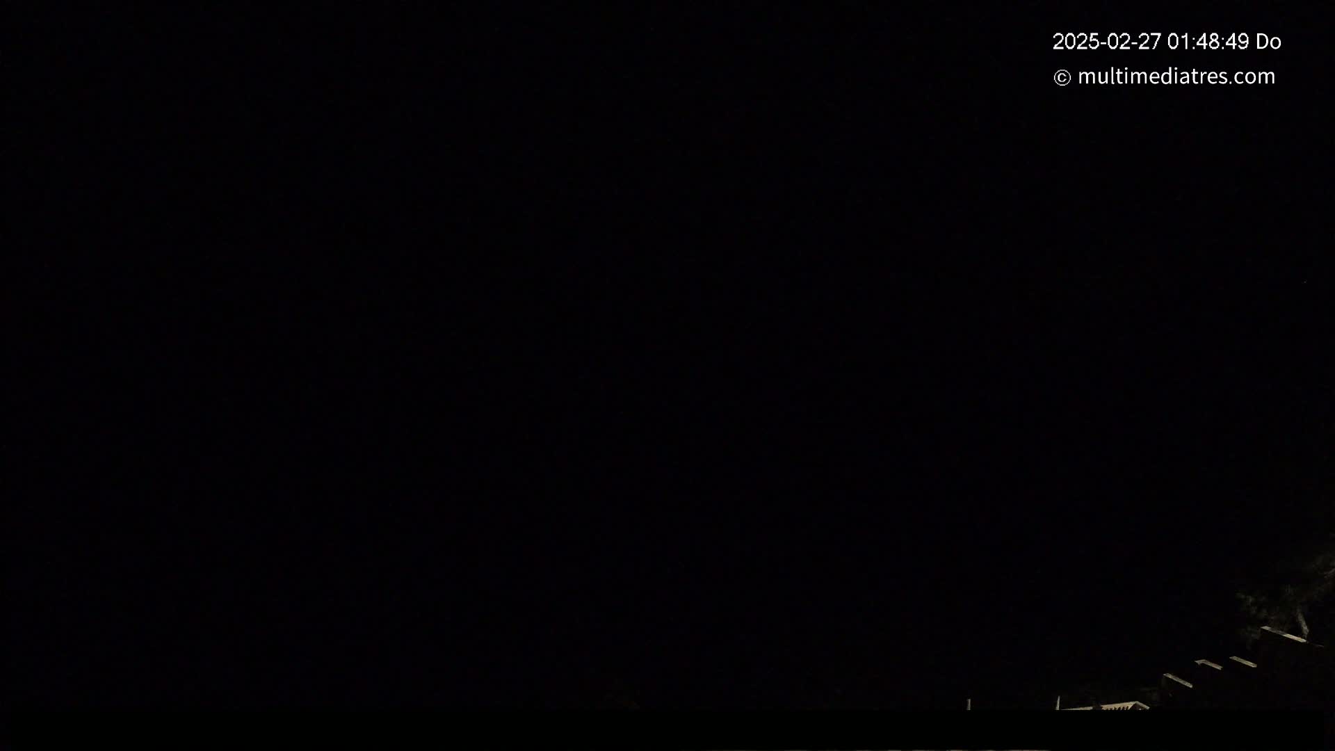 The image shows a very dark, nighttime scene with only a faint suggestion of structures in the bottom right corner.
