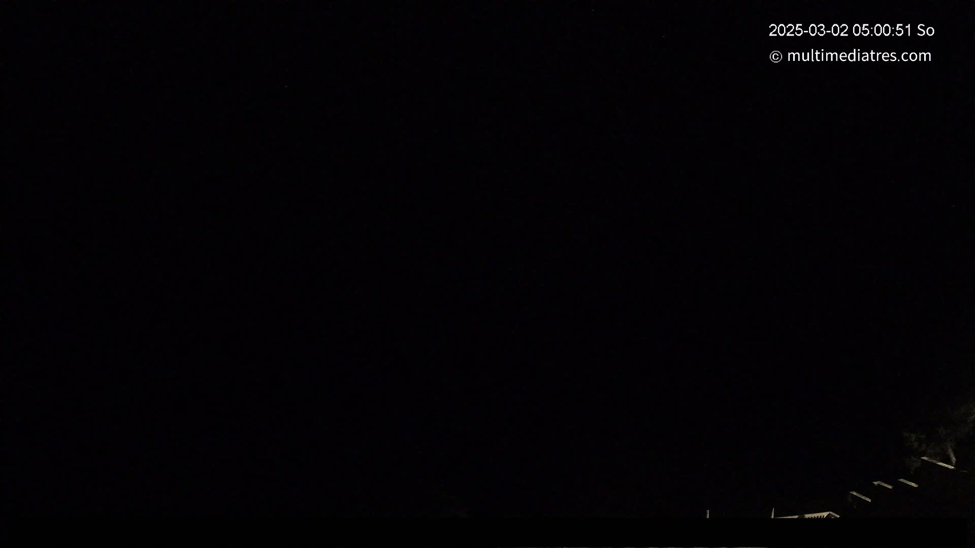A nighttime, dark image shows a few faint lights at the very bottom edge, possibly indicating buildings or structures under a completely black sky.