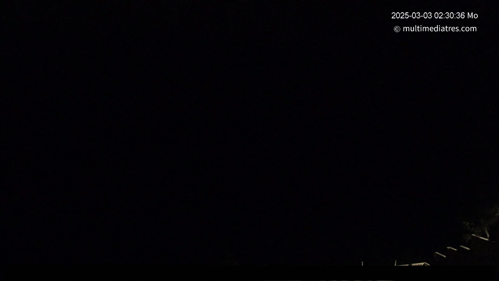 A nighttime scene shows a dark sky and faintly visible structures in the lower right corner.
