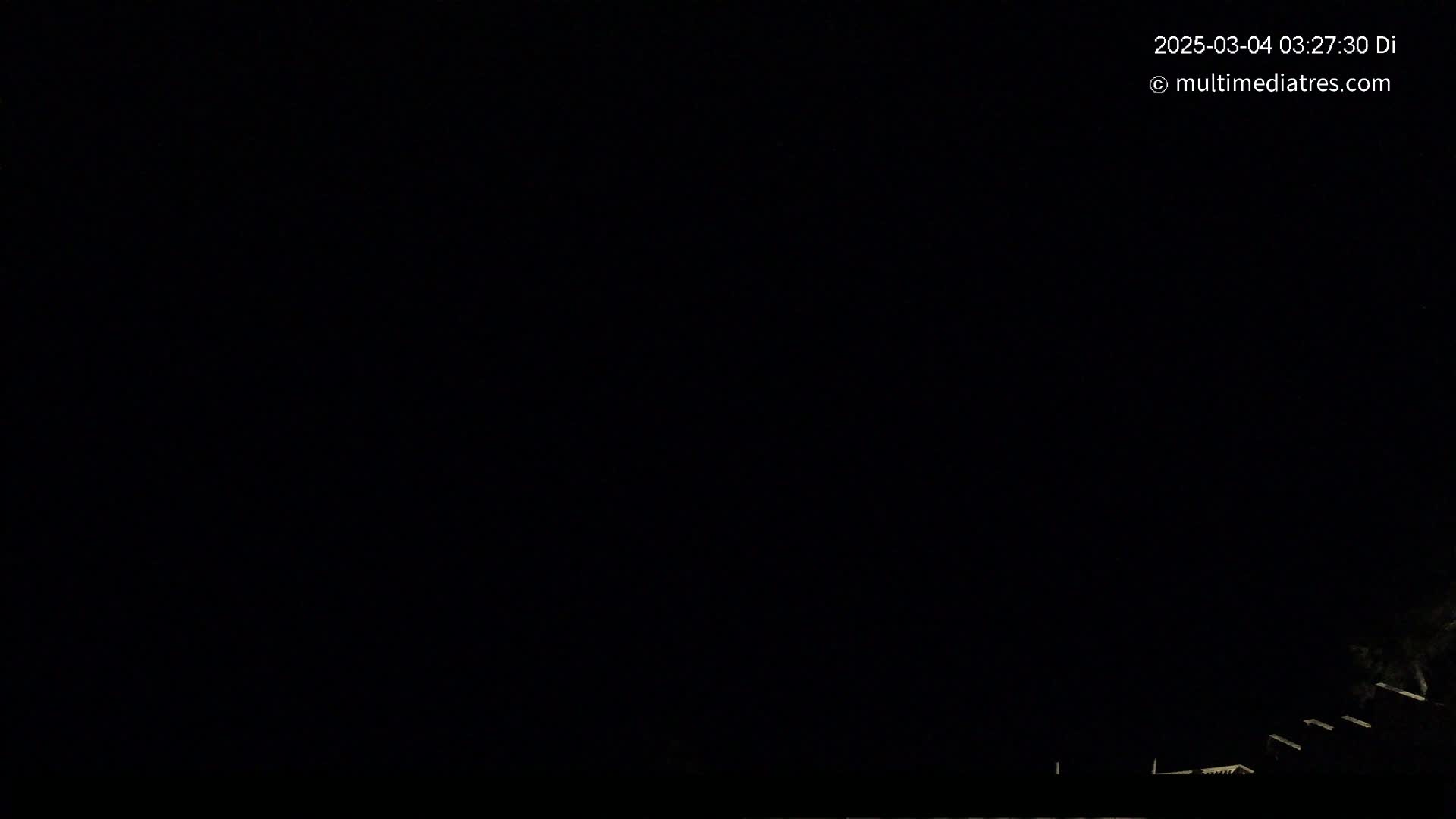 A nighttime outdoor scene shows a dark sky and dimly lit structures at the bottom of the frame.