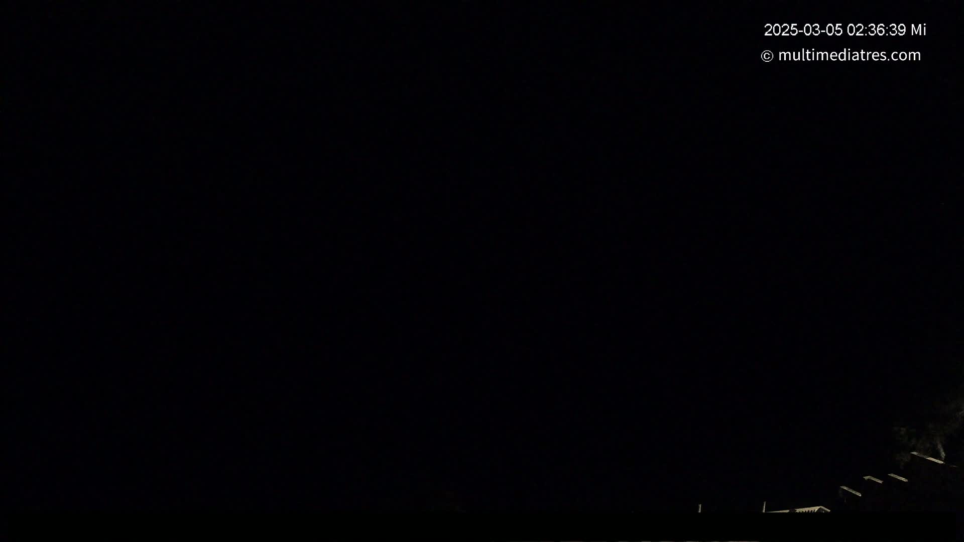 A nighttime outdoor scene shows a dark sky and dimly lit rooftops in the bottom right corner.