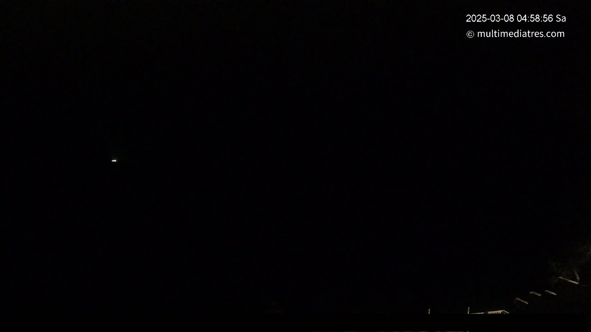 A faint light is visible in a dark, nighttime sky above a low-lying structure.