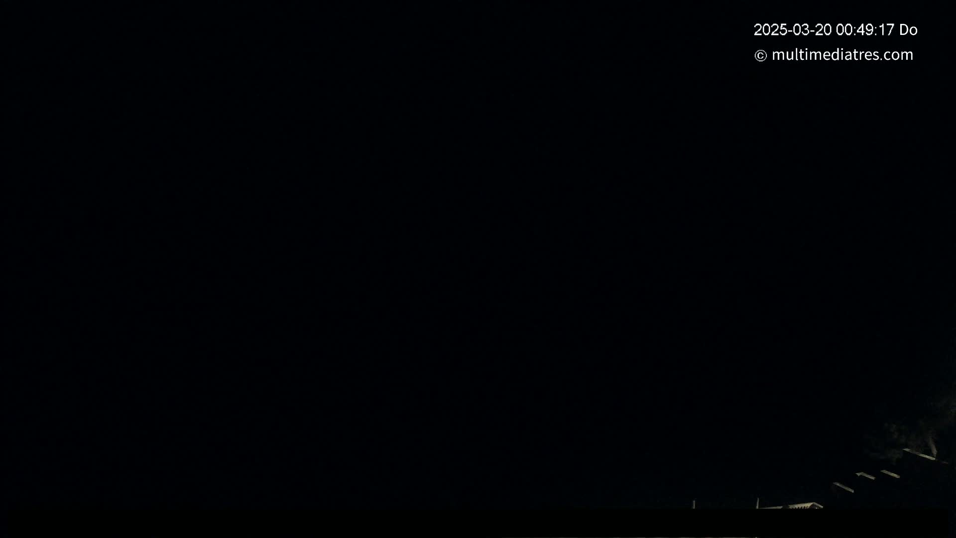 The image shows a very dark nighttime scene with a few faintly visible structures at the very bottom.