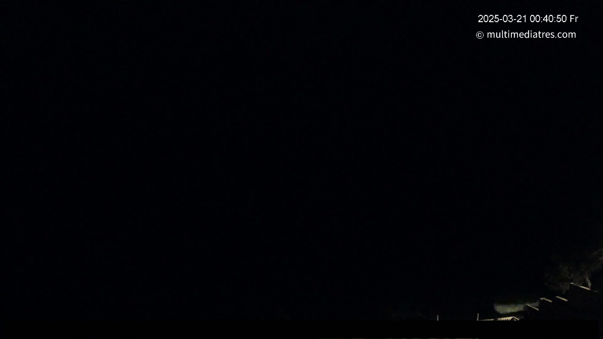 A nighttime image shows a dark sky and the faint outlines of buildings and trees in the bottom right corner.