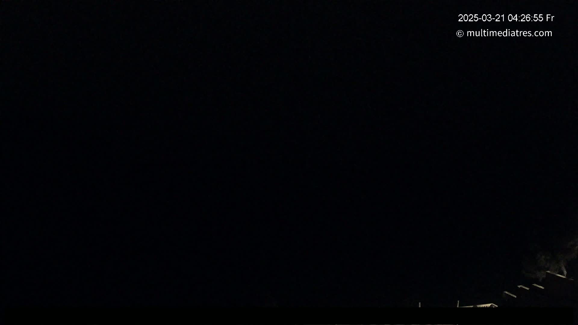 A nighttime scene shows dimly lit rooftops and a very dark sky.