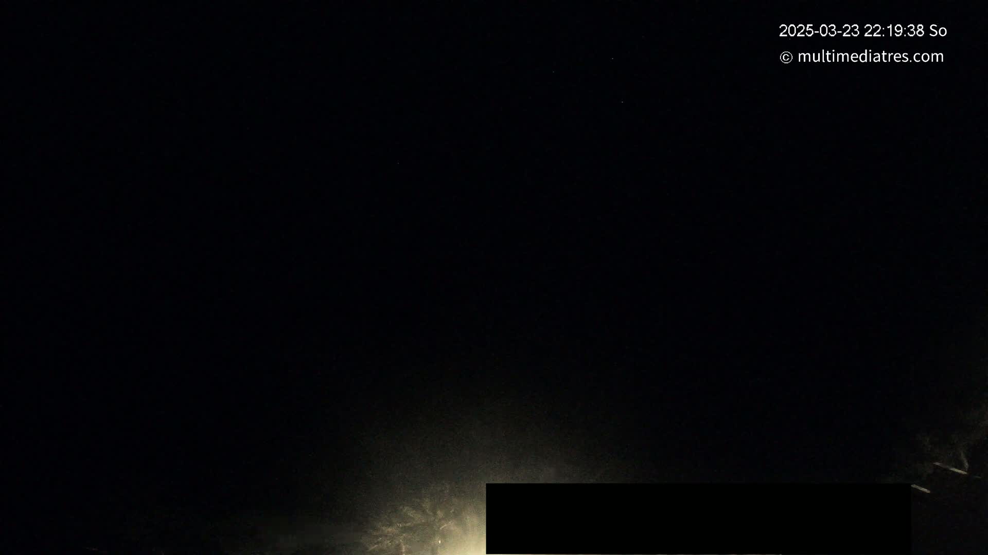 A nighttime, dark scene is illuminated by a low light source near the bottom, with a dark, rectangular object obscuring part of the view.