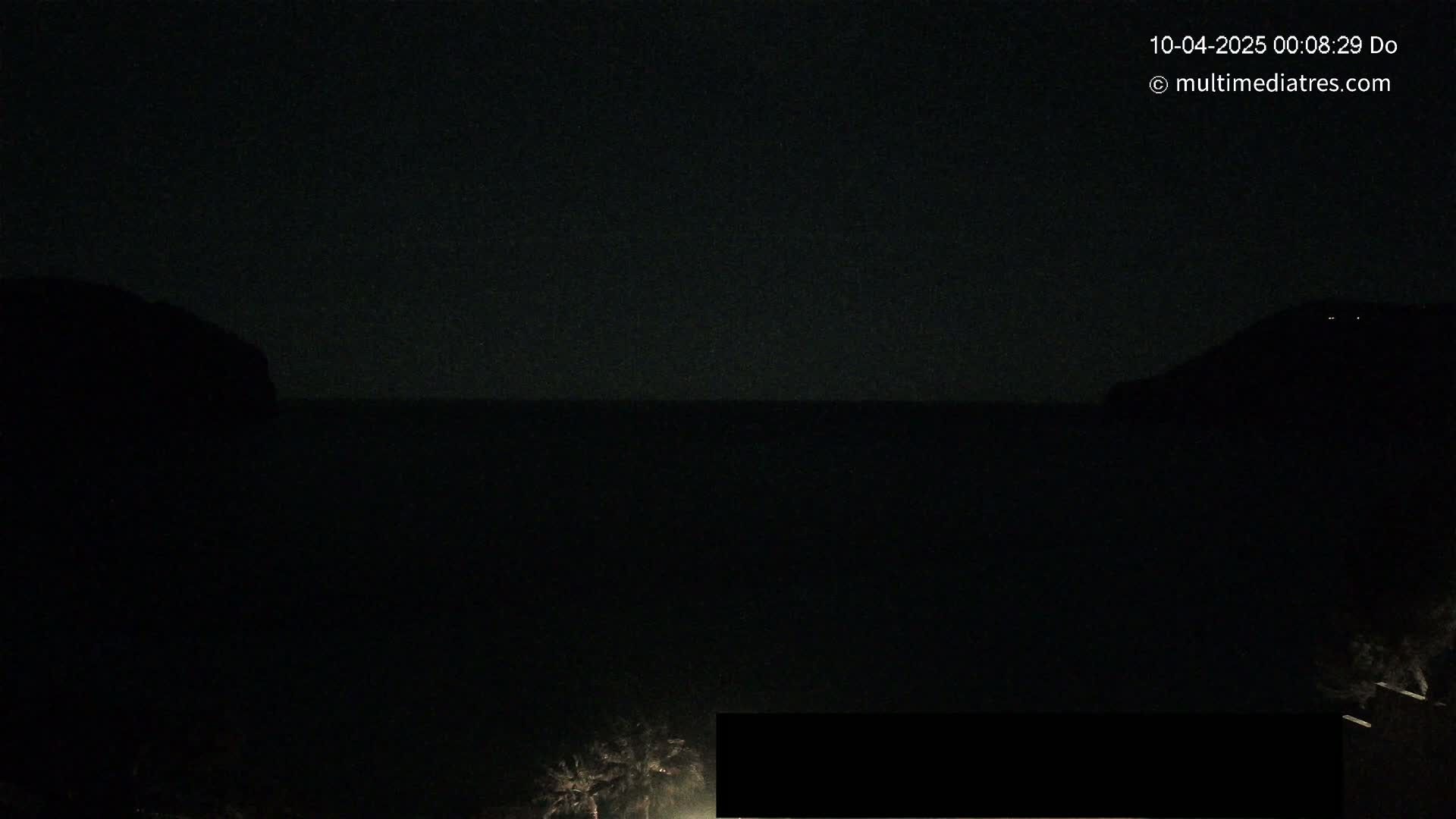A nighttime, dark ocean scene is shown, with silhouetted landmasses on either side.