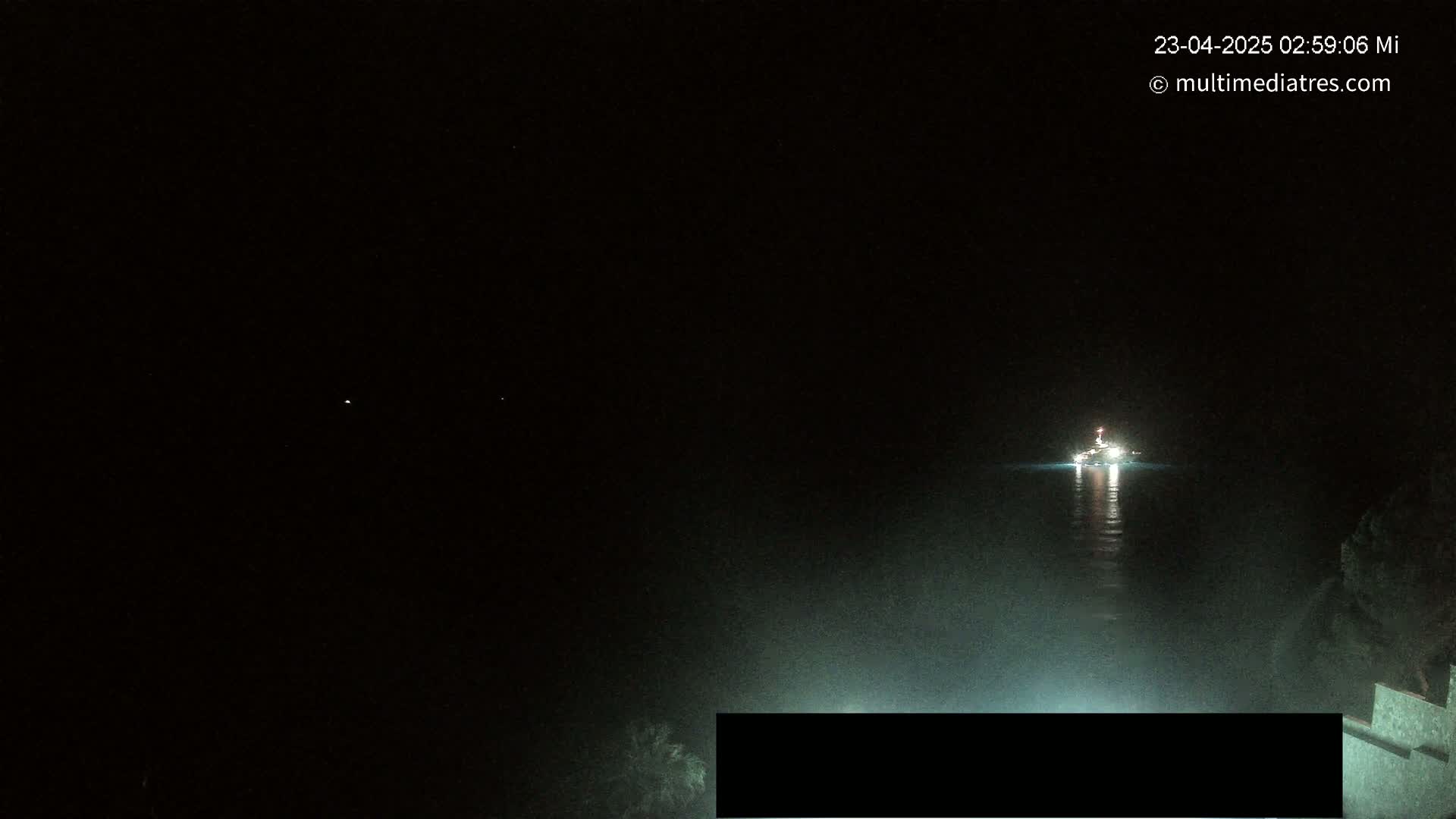 A brightly lit boat is visible on a dark body of water at night.