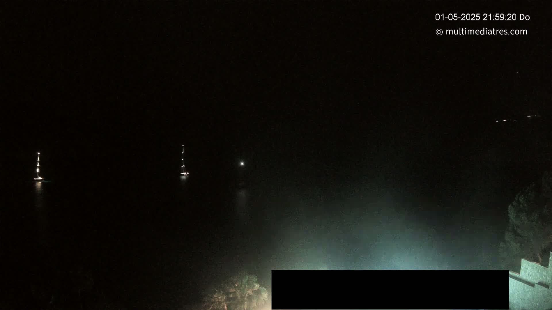 Two boats are visible on a dark body of water at night.