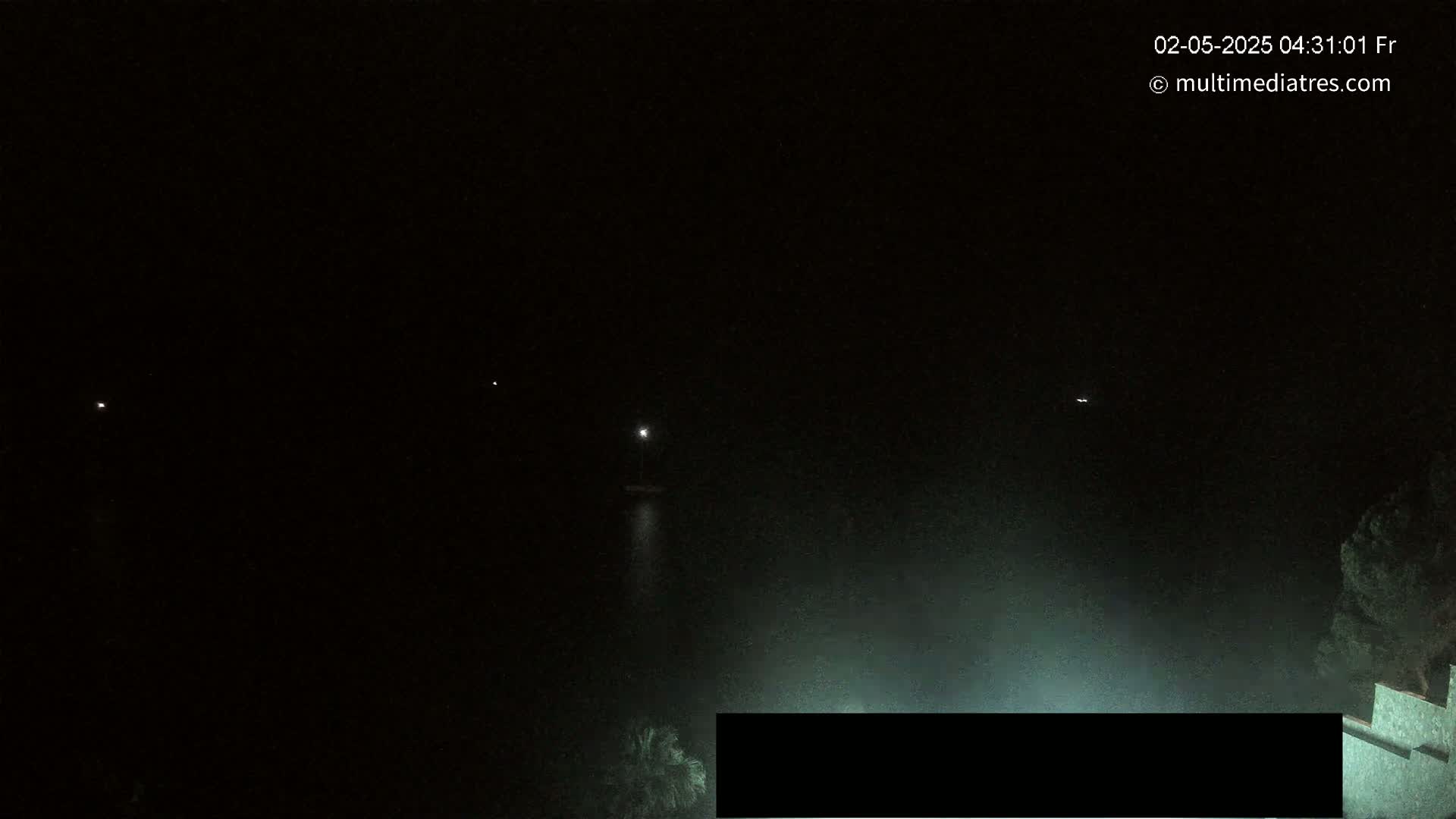 A nighttime, hazy view shows a few distant lights and a partially obscured structure below.
