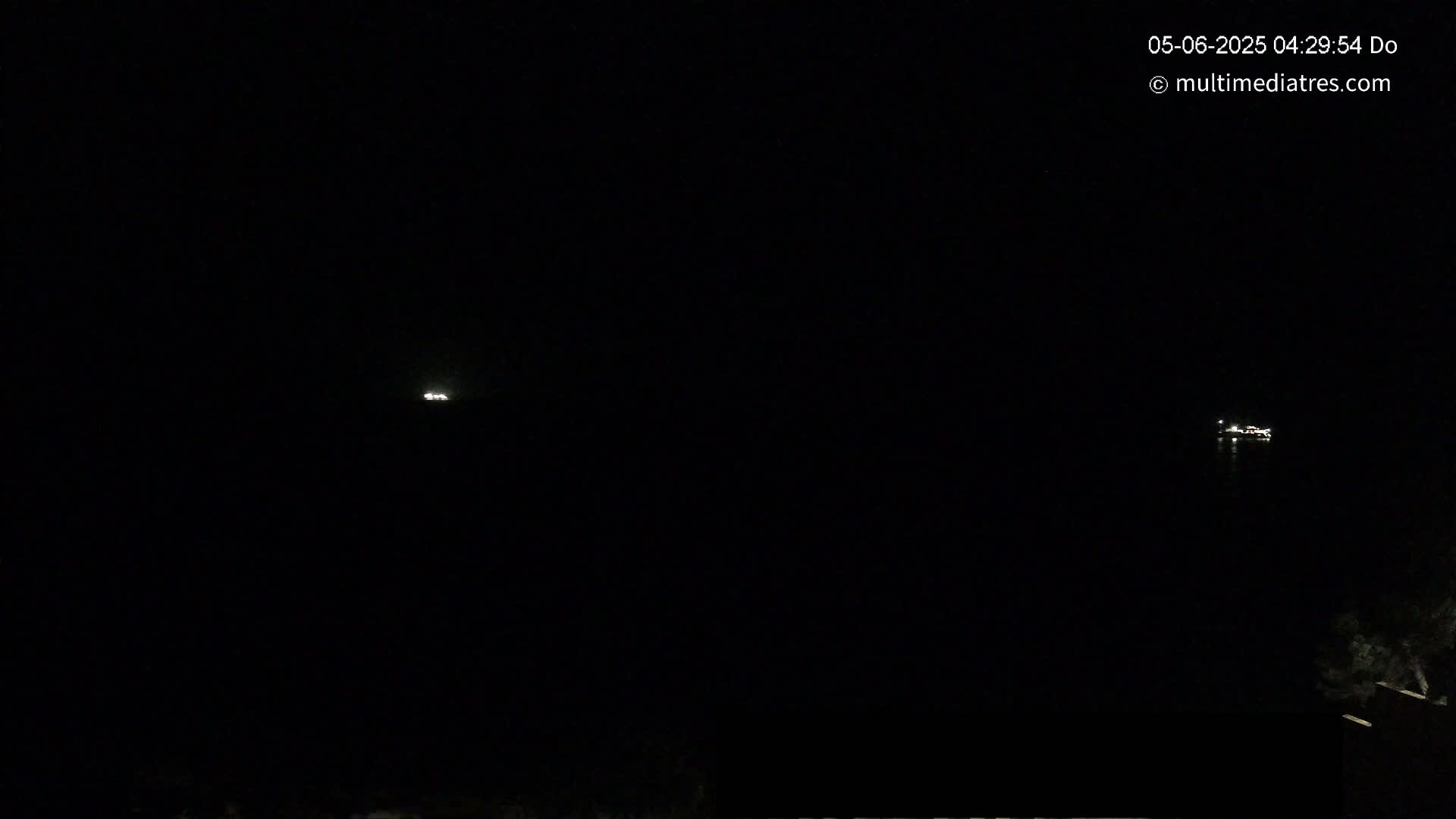 Two small, distant lights are visible on dark water under a nighttime sky.