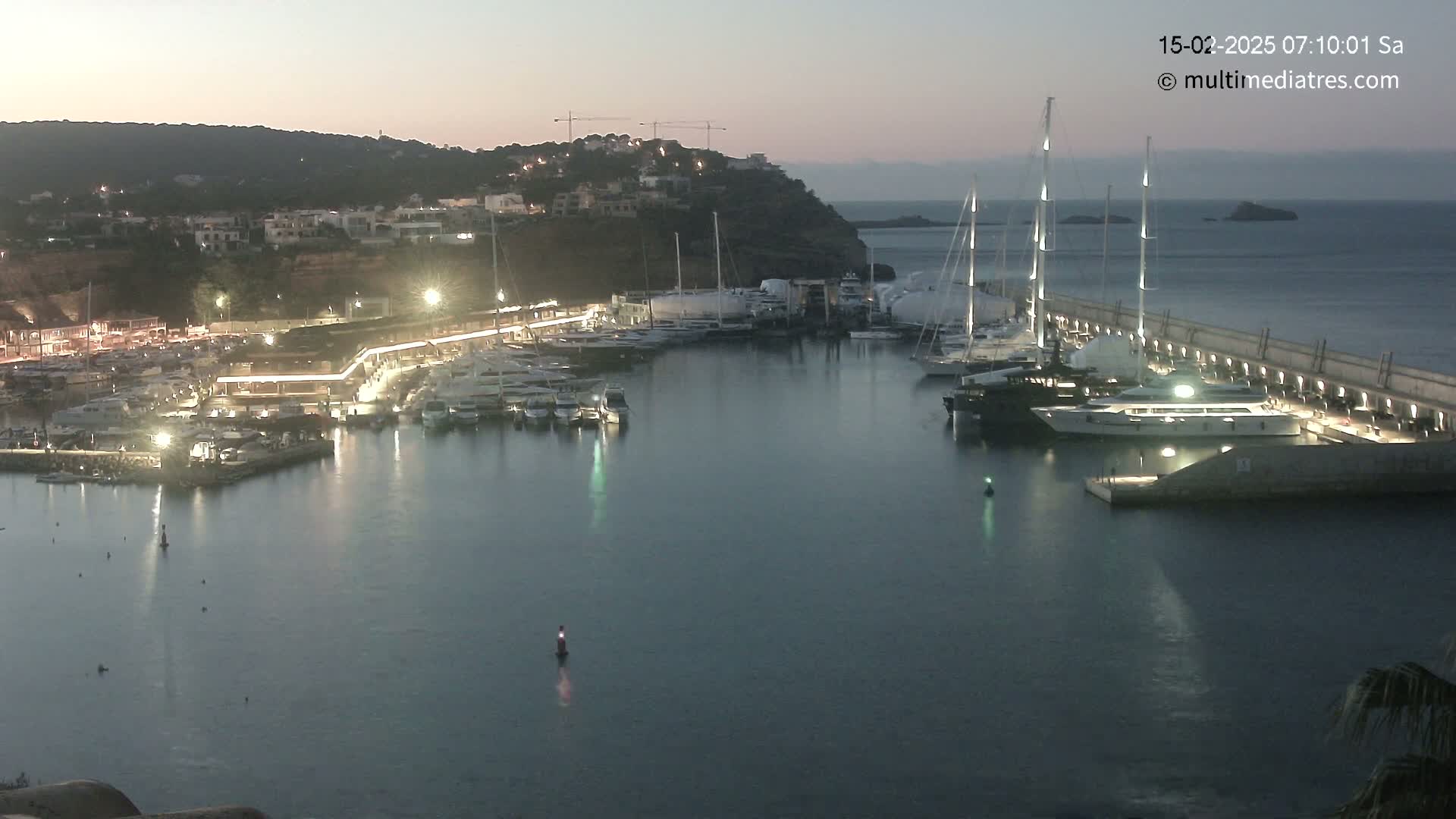 A marina filled with yachts and boats at twilight, under a clear, dusky sky.
