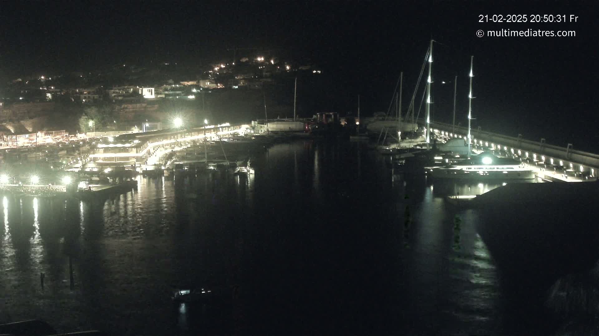 A nighttime view of a harbor filled with boats and lit buildings along the shore.