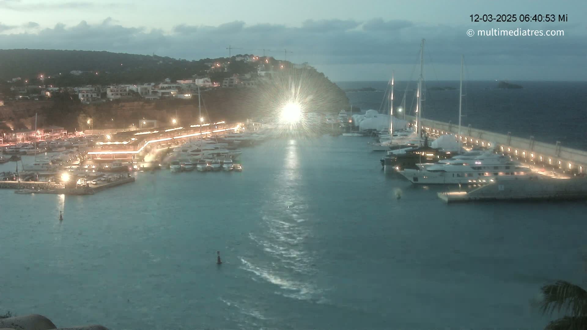 A marina filled with boats at dusk under a partly cloudy sky.