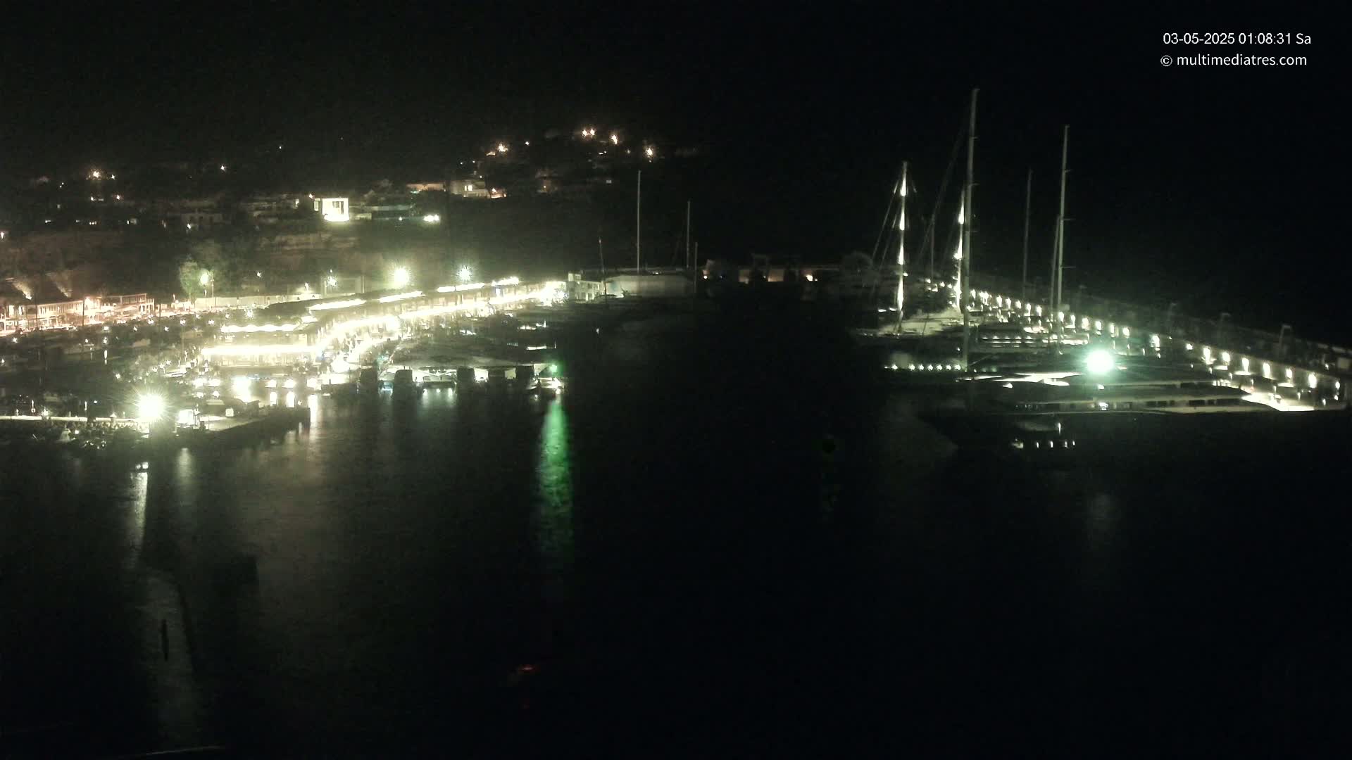 A nighttime view of a harbor filled with boats and illuminated buildings along the shoreline.