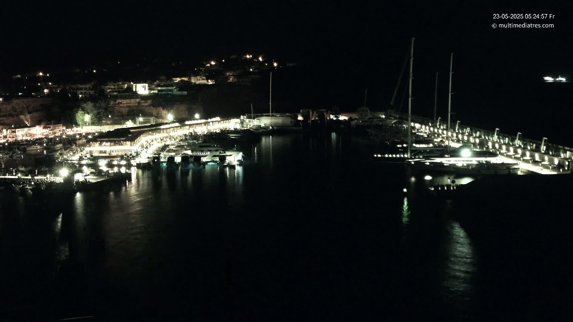 A nighttime view of a harbor filled with boats and lit buildings along the shoreline.