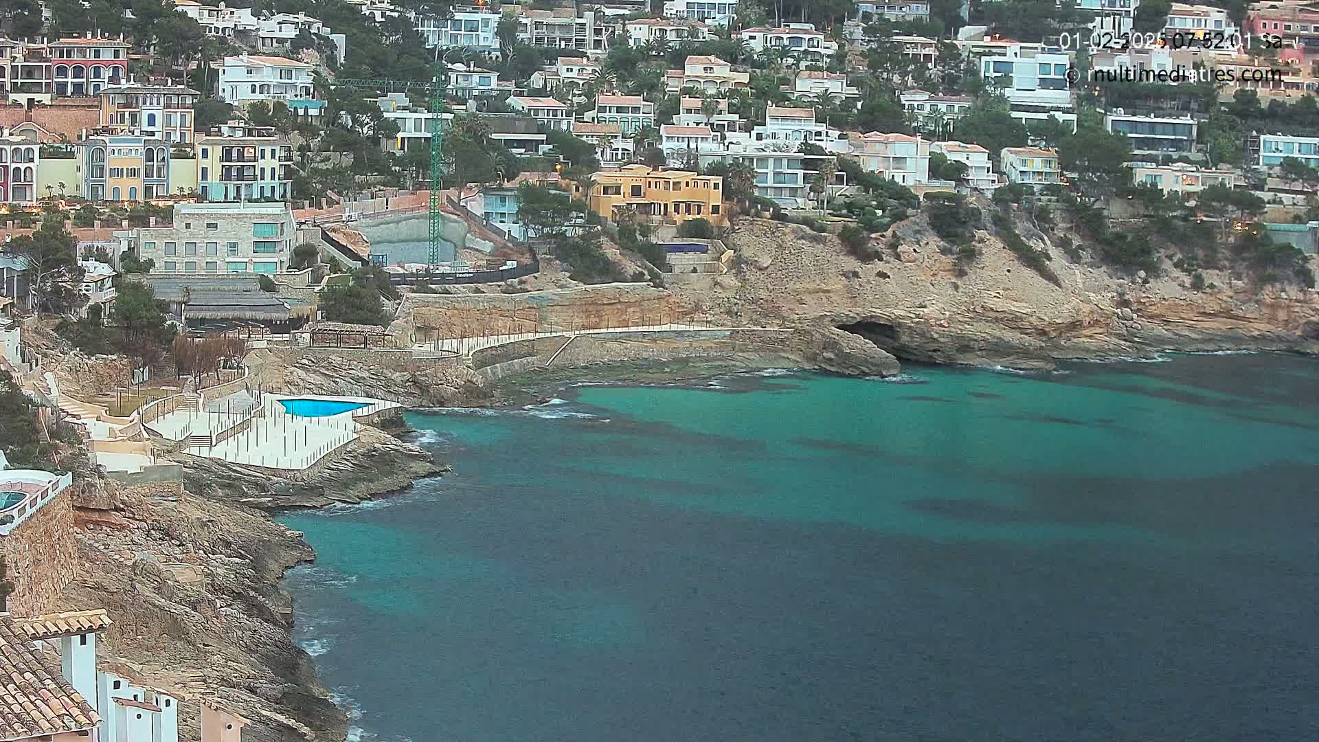 A coastal area with numerous houses built into a hillside overlooking a teal-colored ocean.