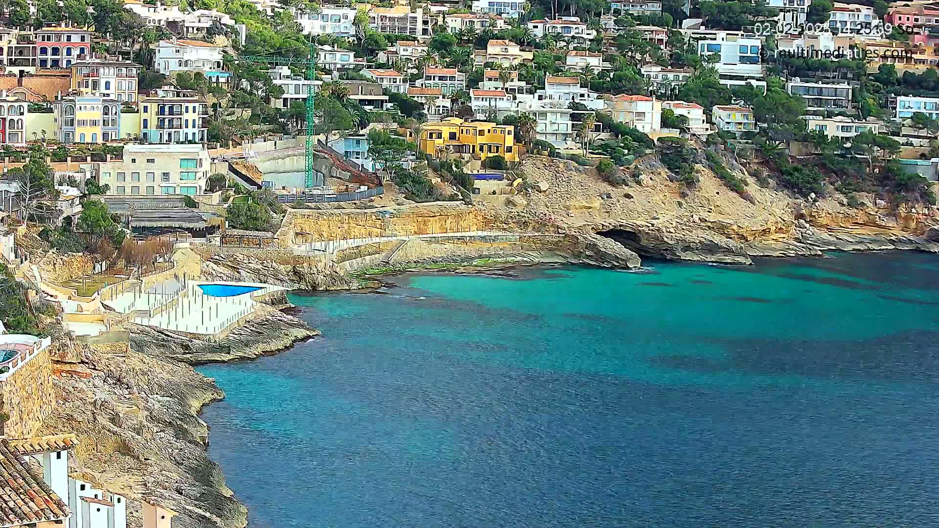 A coastal town with numerous houses built on a hillside overlooking a clear, turquoise ocean.