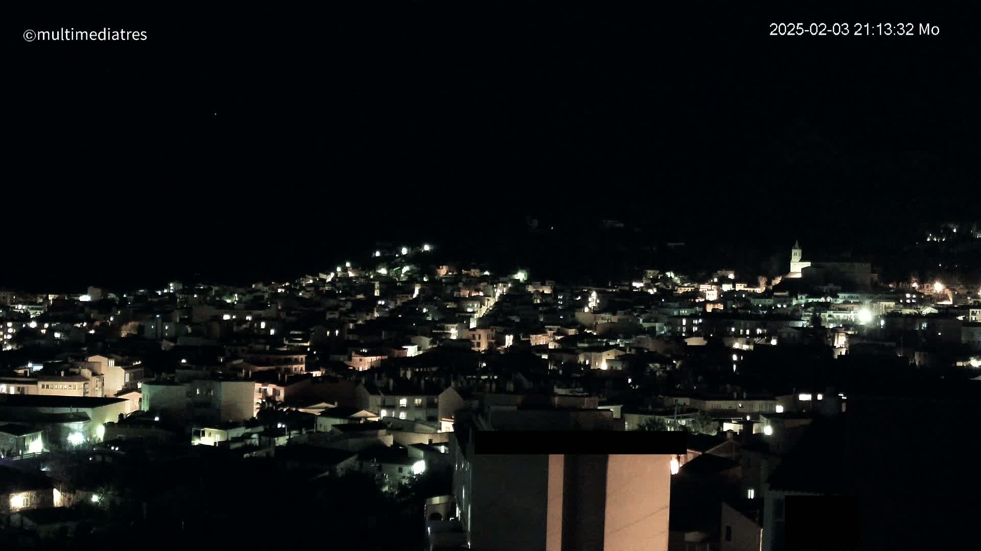 A nighttime, aerial view of a town illuminated by its lights under a clear, dark sky.