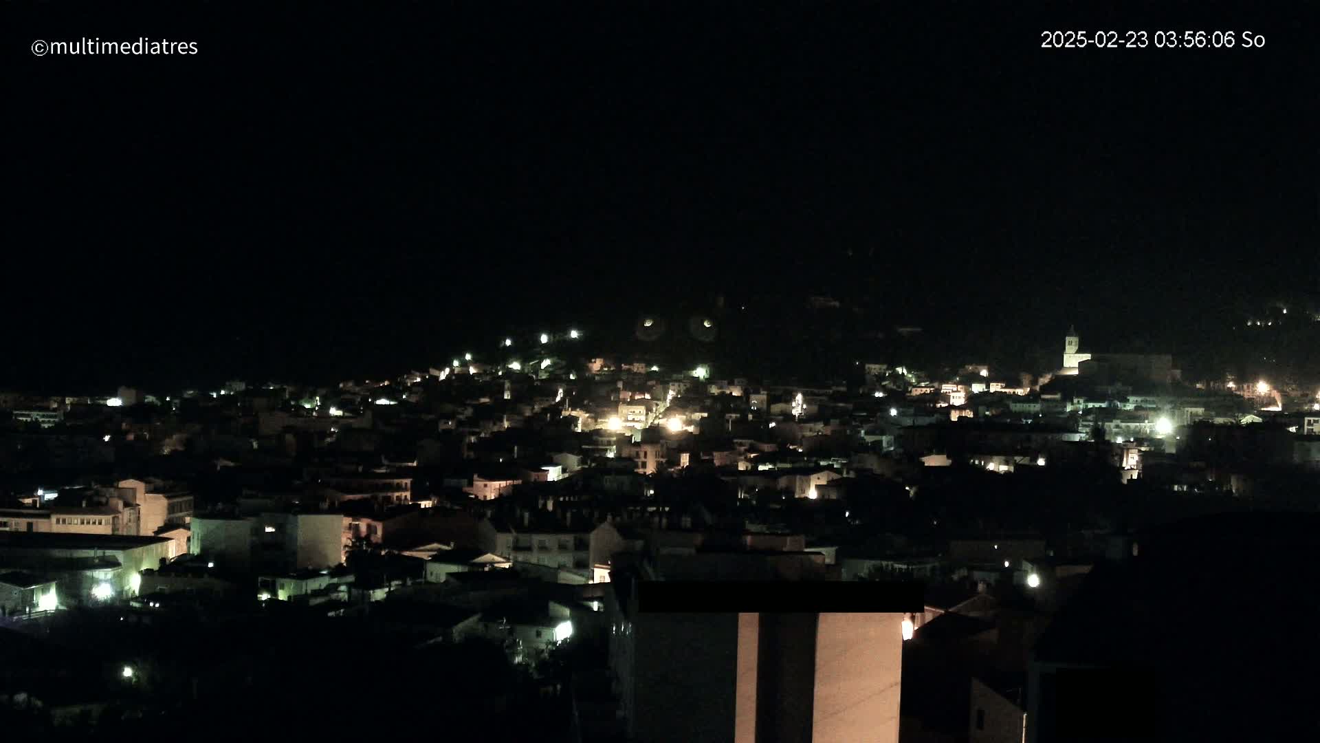 A nighttime view of a town illuminated by scattered lights under a clear, dark sky.