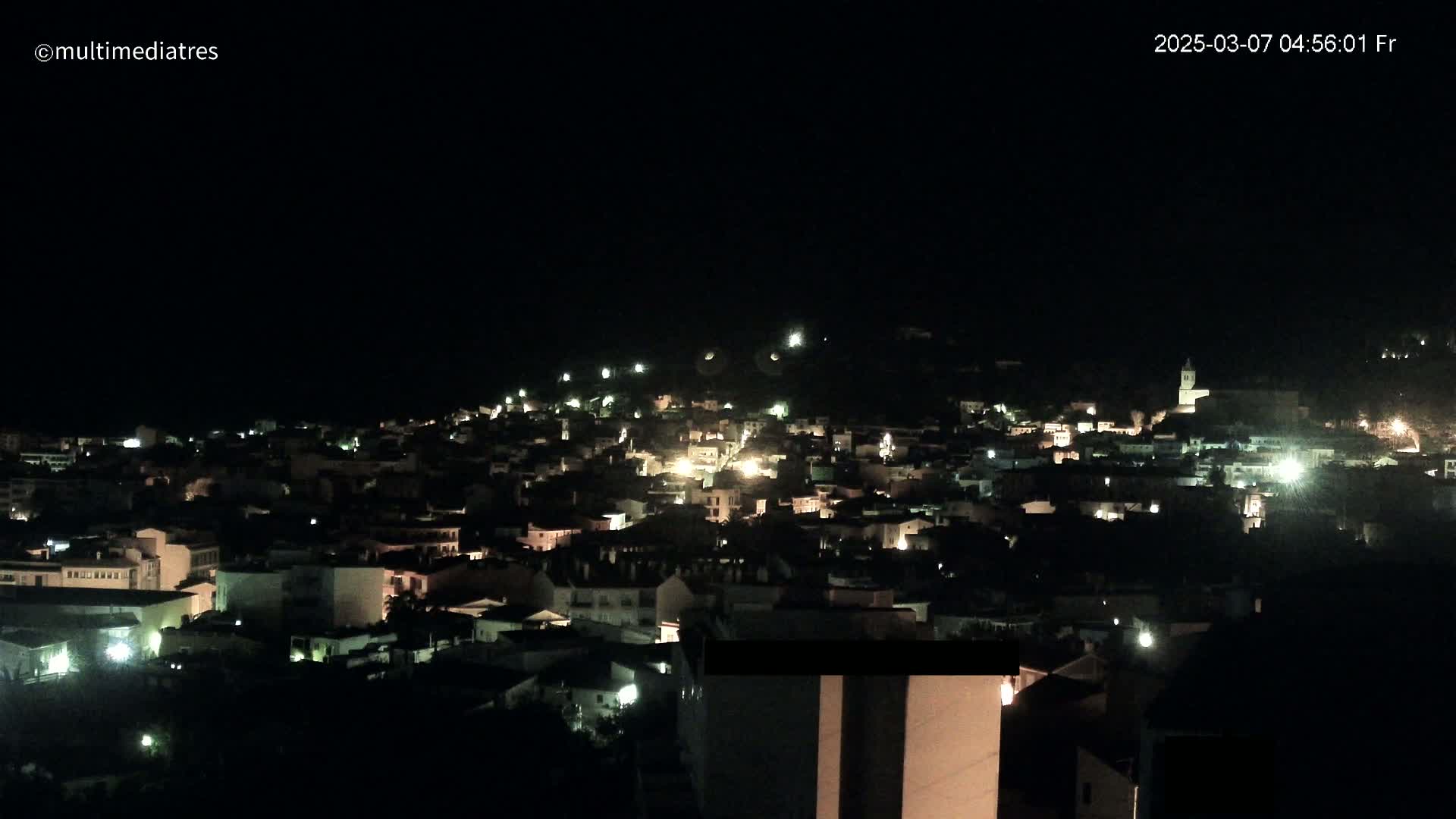 A nighttime, aerial view of a town illuminated by scattered lights under a clear, dark sky.