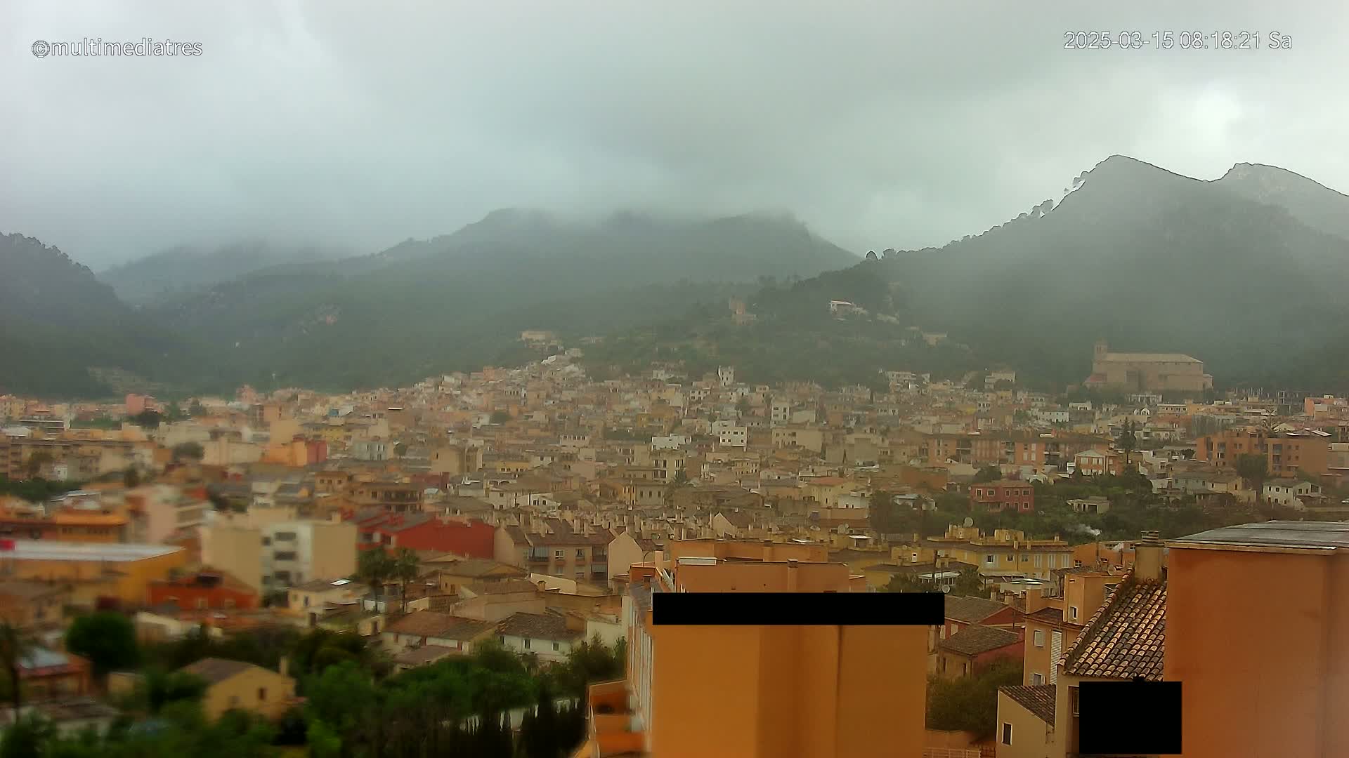 A rain-covered town nestled in a valley between misty mountains.