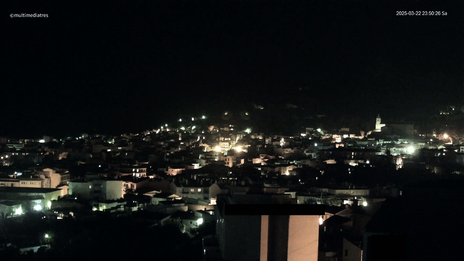 A nighttime, aerial view of a town illuminated by scattered lights.