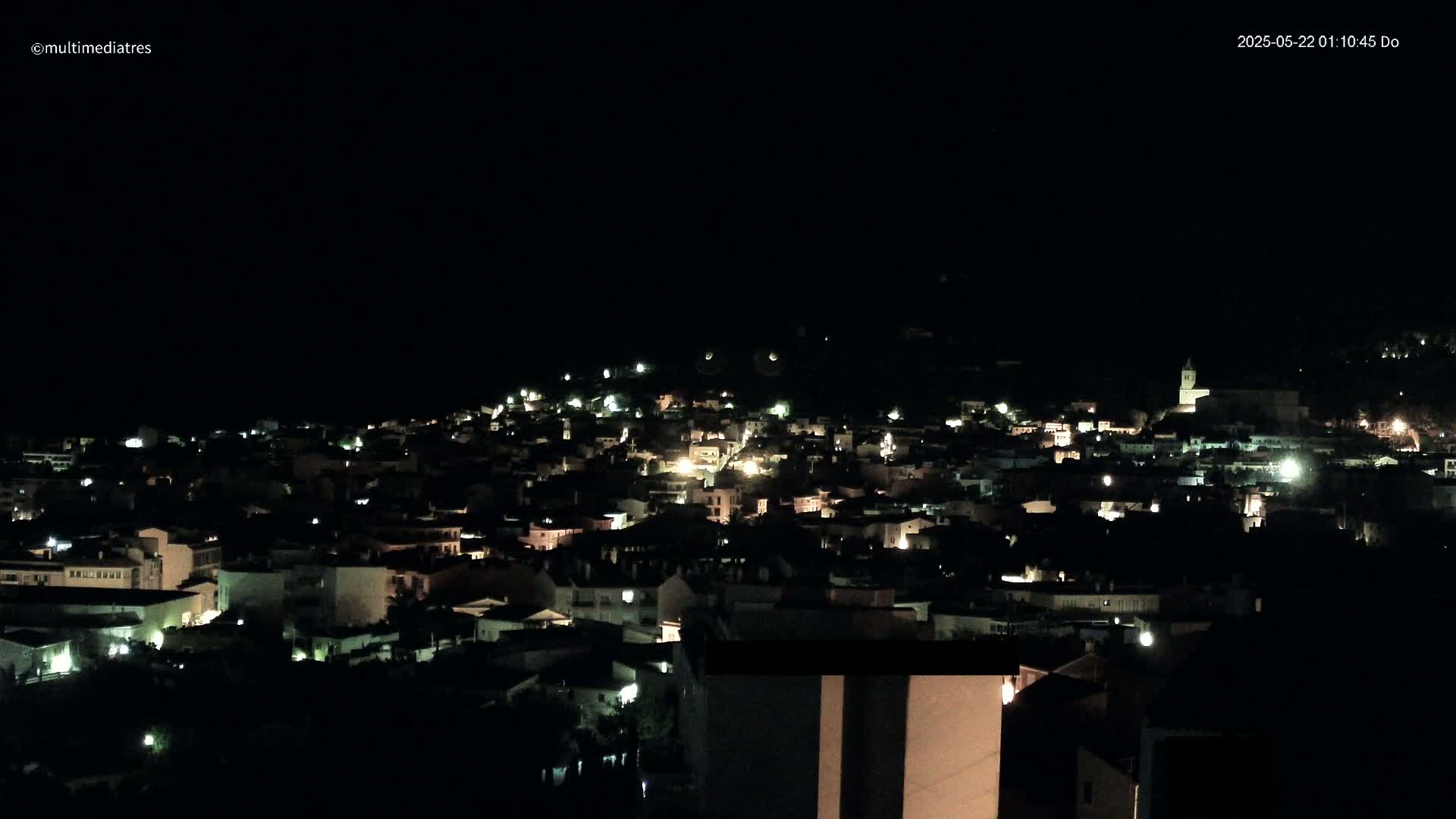 A nighttime view of a town illuminated by scattered lights under a clear, dark sky.