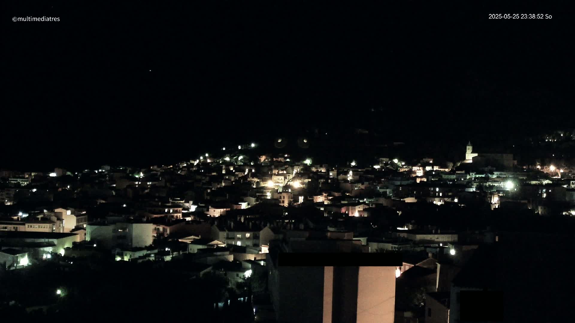 A nighttime, aerial view of a town illuminated by scattered lights under a clear, dark sky.