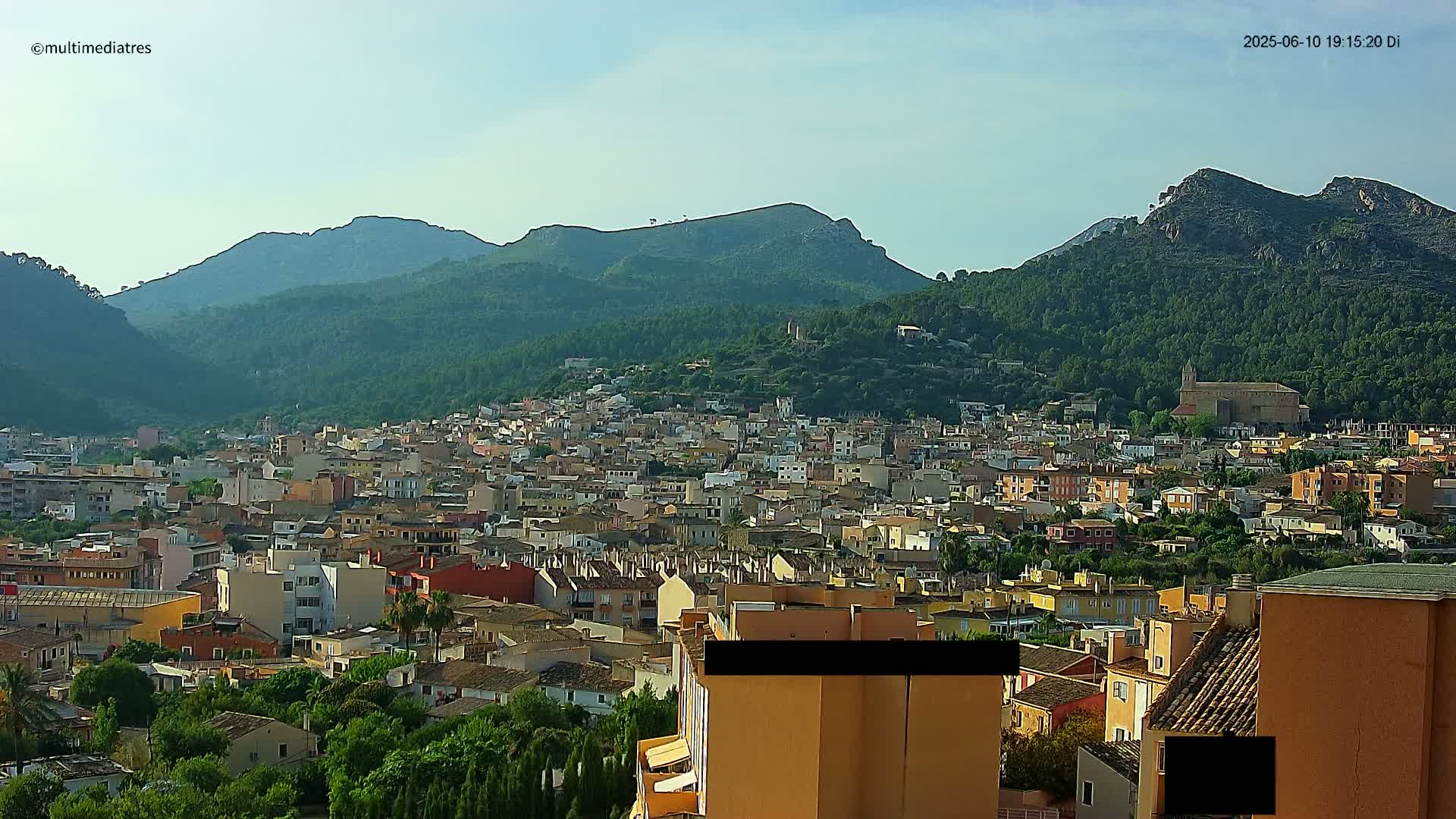 A sprawling town nestled in a valley, surrounded by lush green mountains under a clear sky.