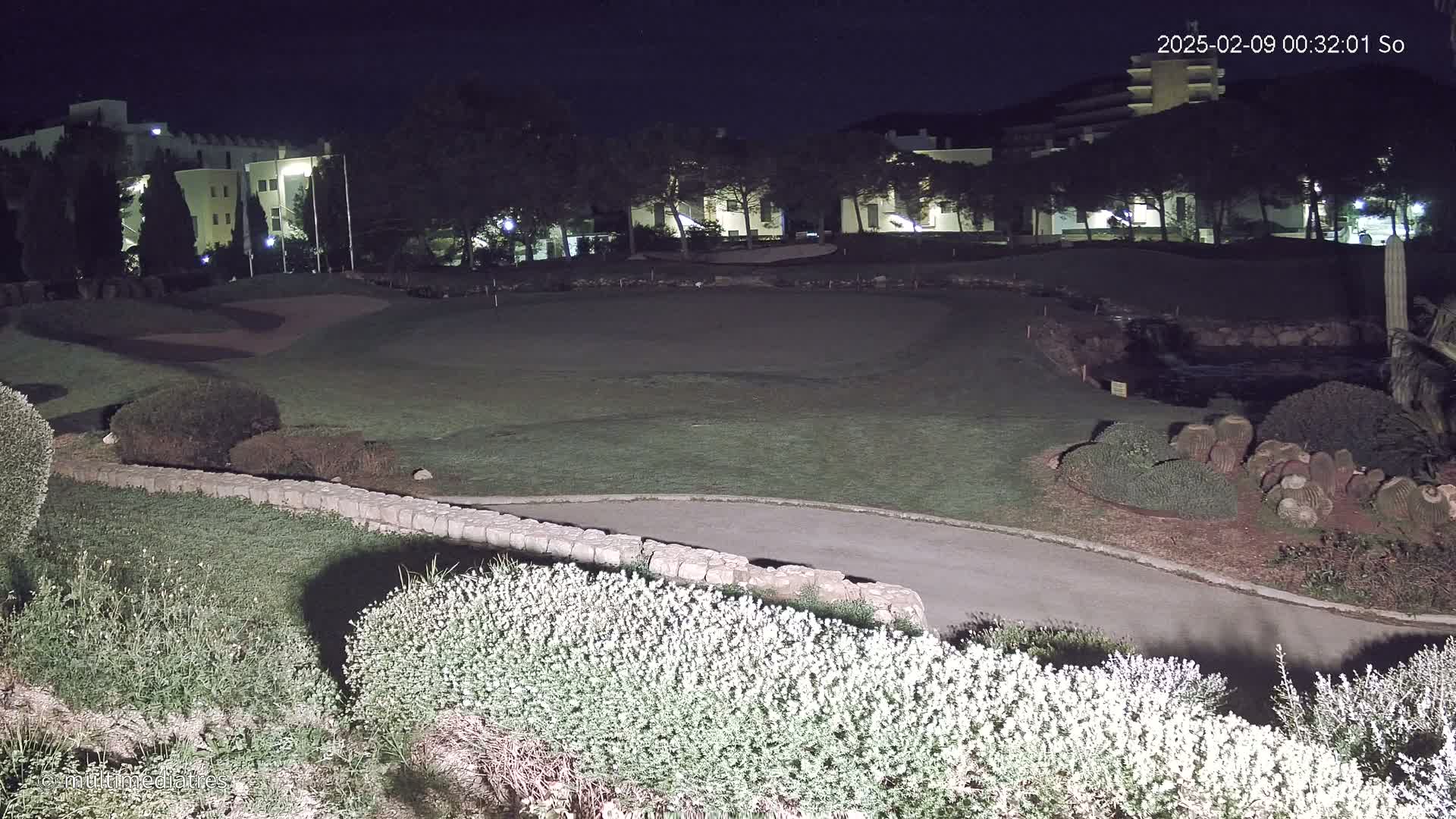 A nighttime view of a golf course with a building in the background under a clear, dark sky.