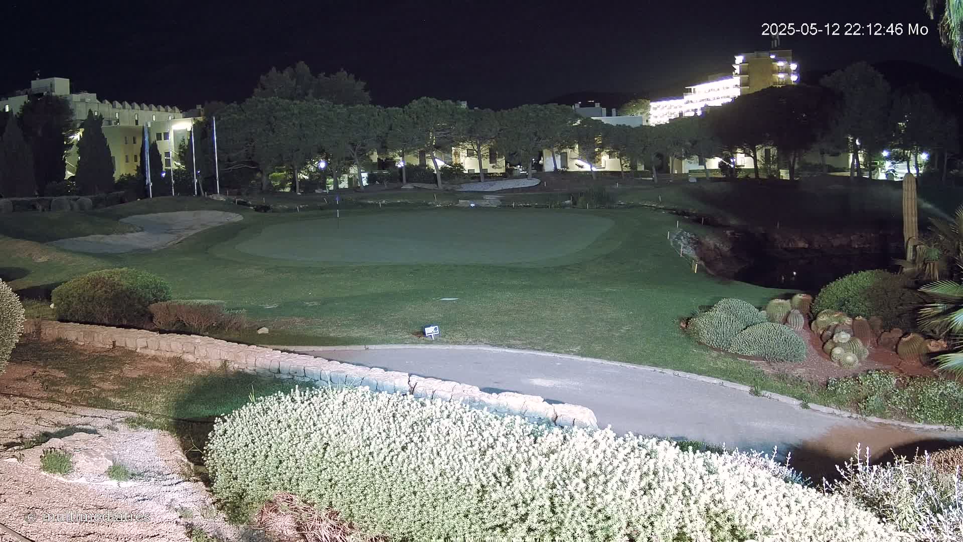 A nighttime view of a lit-up golf course next to a building complex.