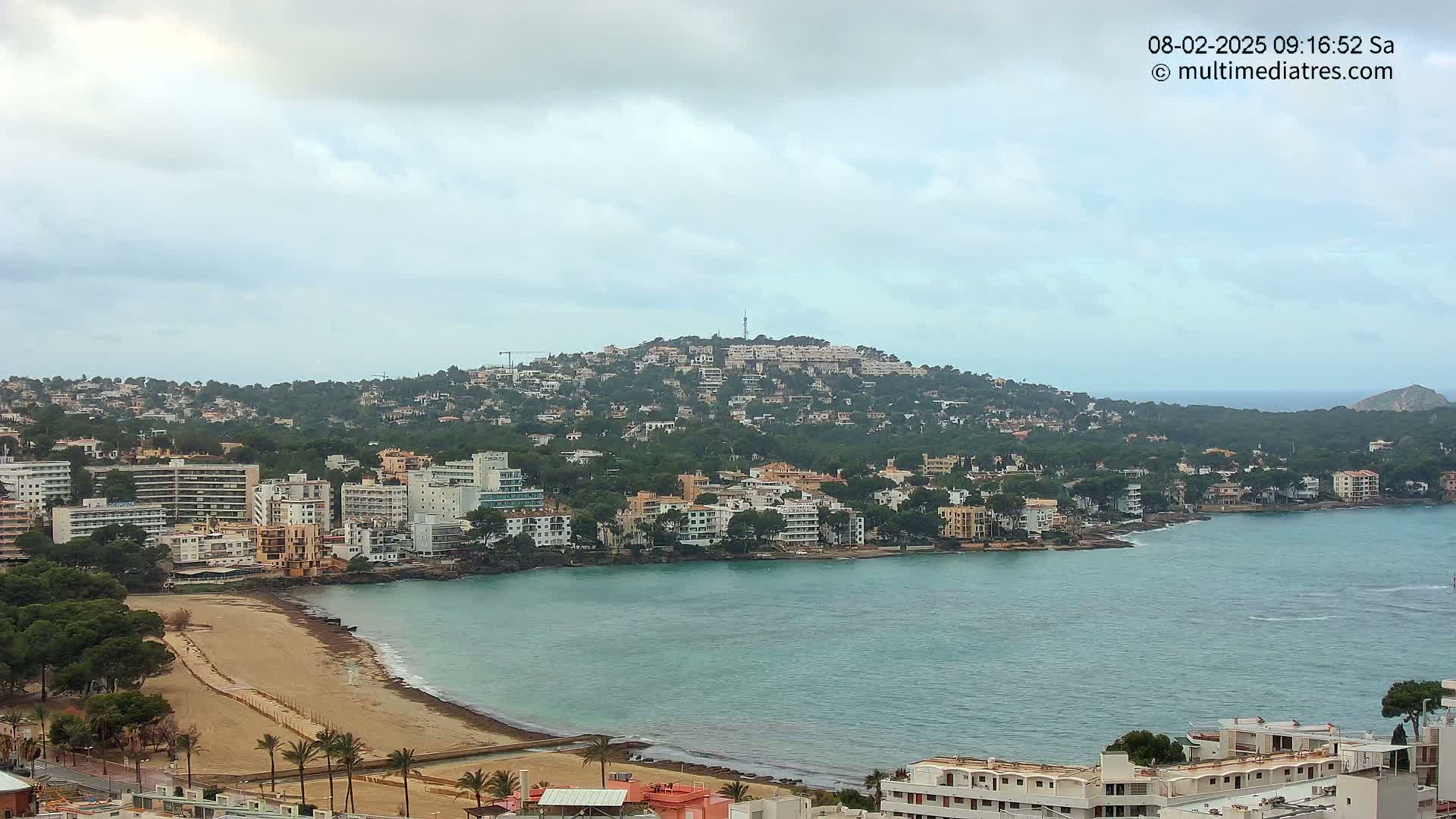 A coastal town with buildings clustered around a bay under a cloudy sky.