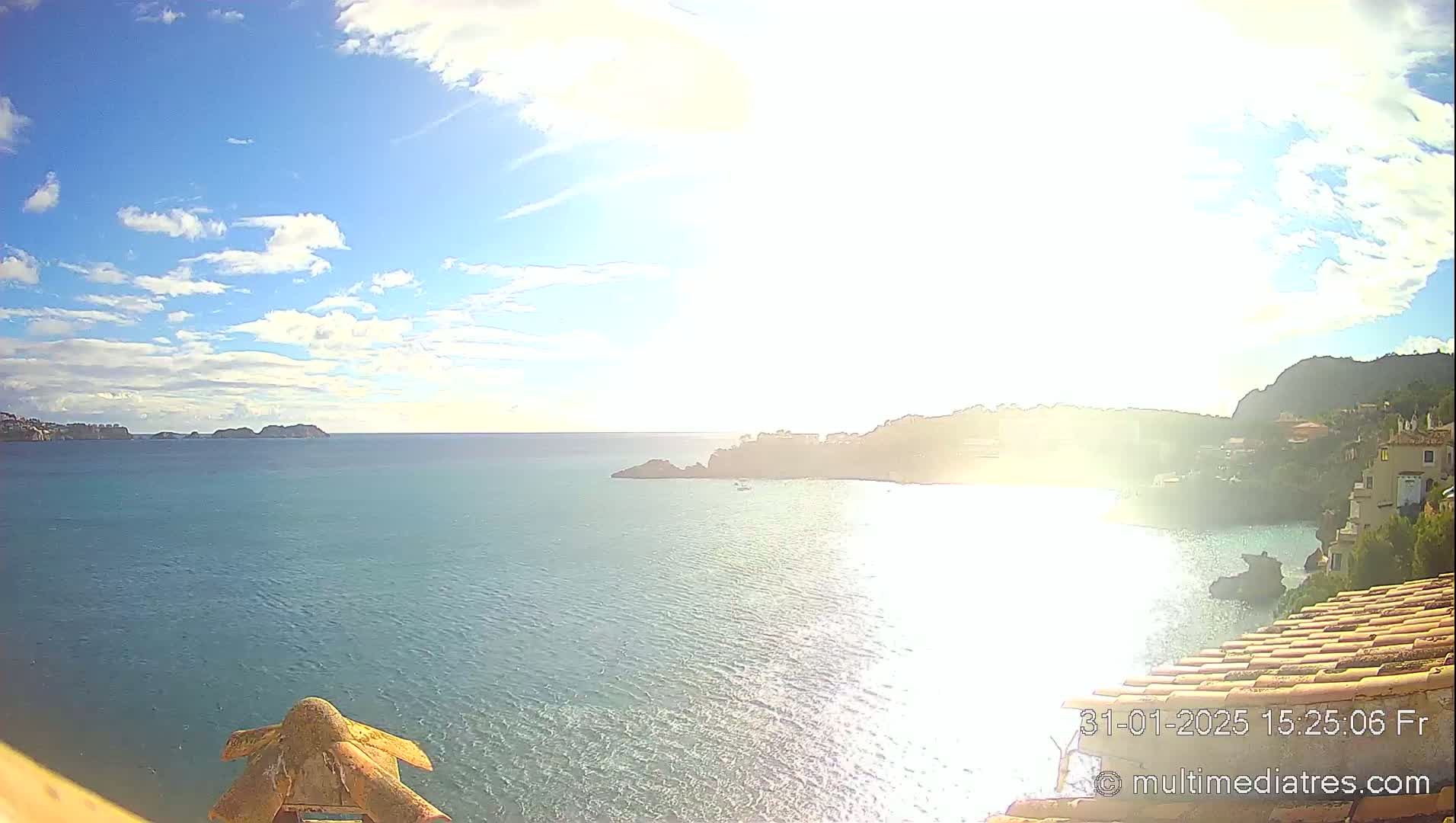A sunny day overlooking a calm sea with a distant coastline and a few buildings visible on the right.