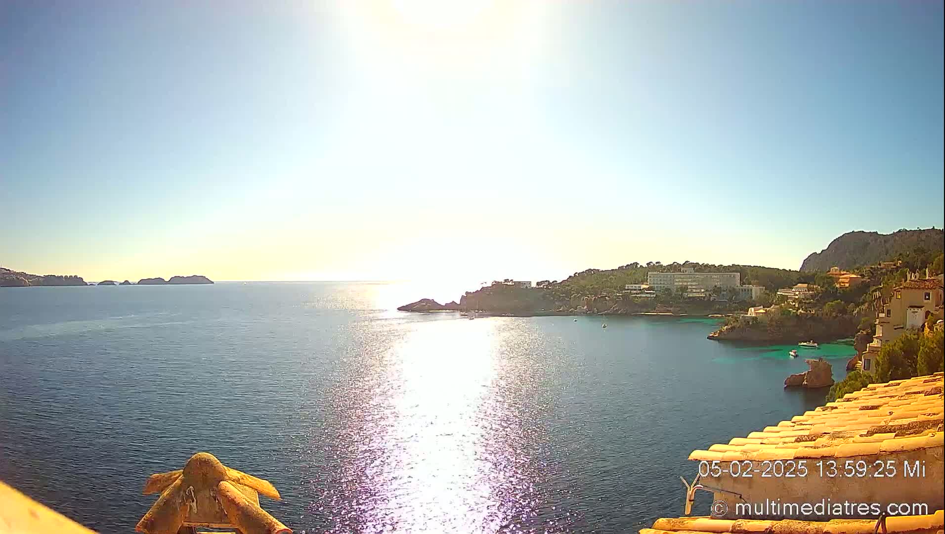 A sunny day overlooking a calm bay with a coastline of buildings and small islands in the distance.