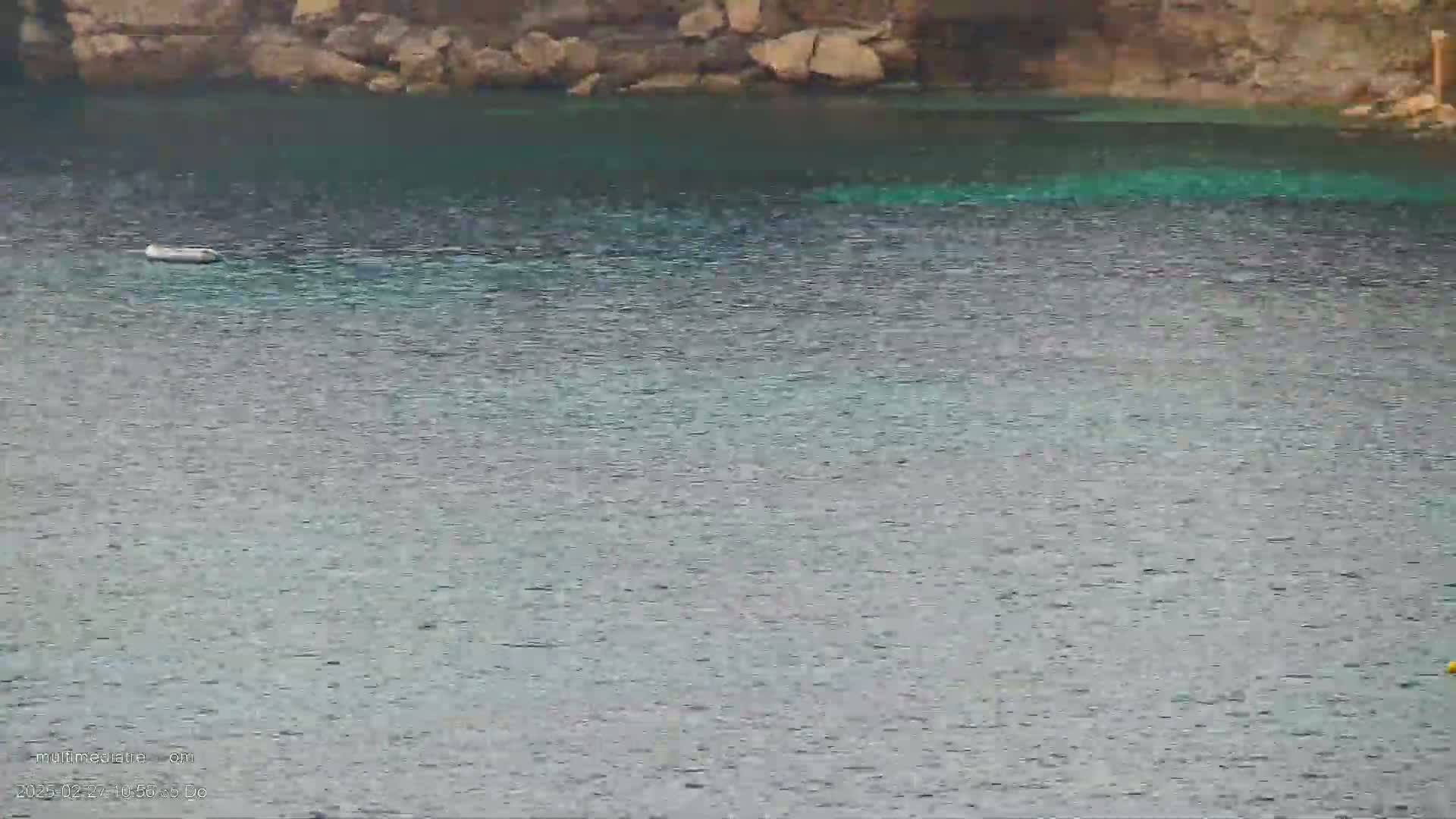 A small, calm body of teal water is nestled against a rocky shoreline.