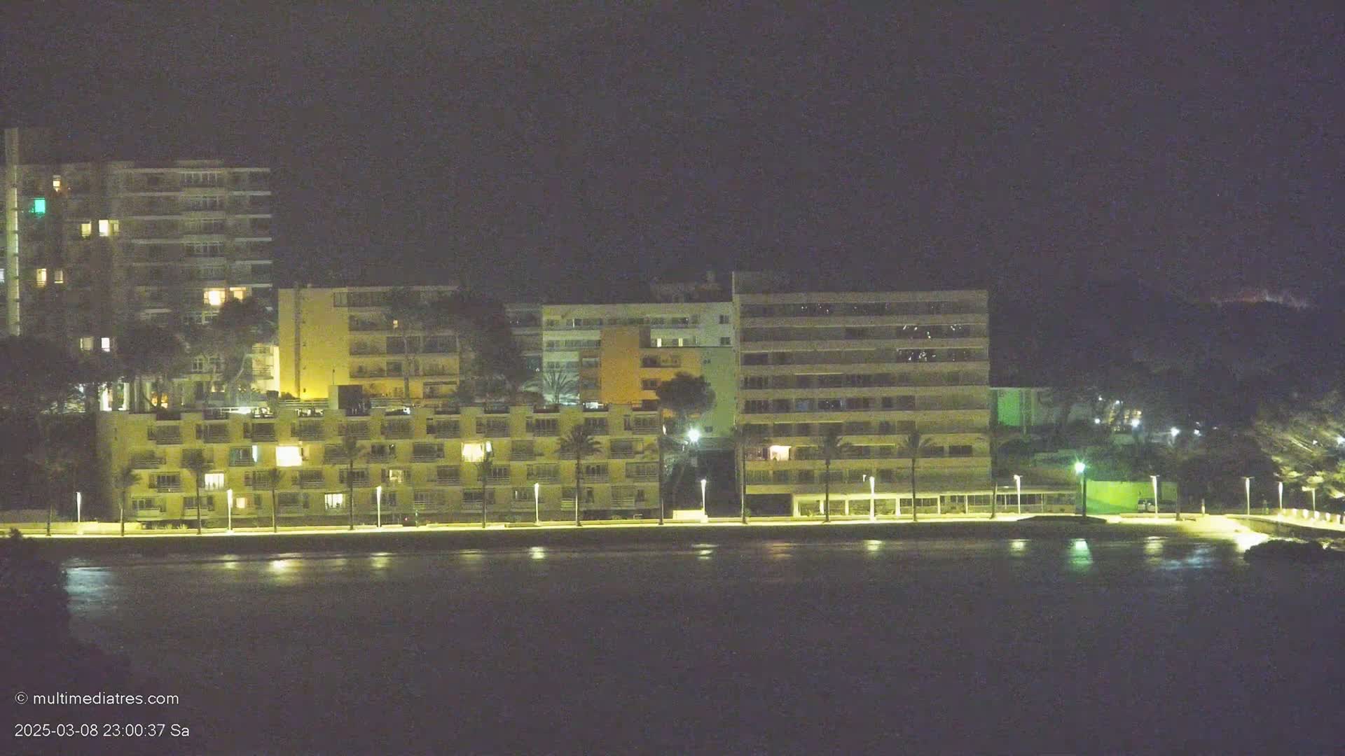 A line of illuminated buildings sits on a waterfront at night.