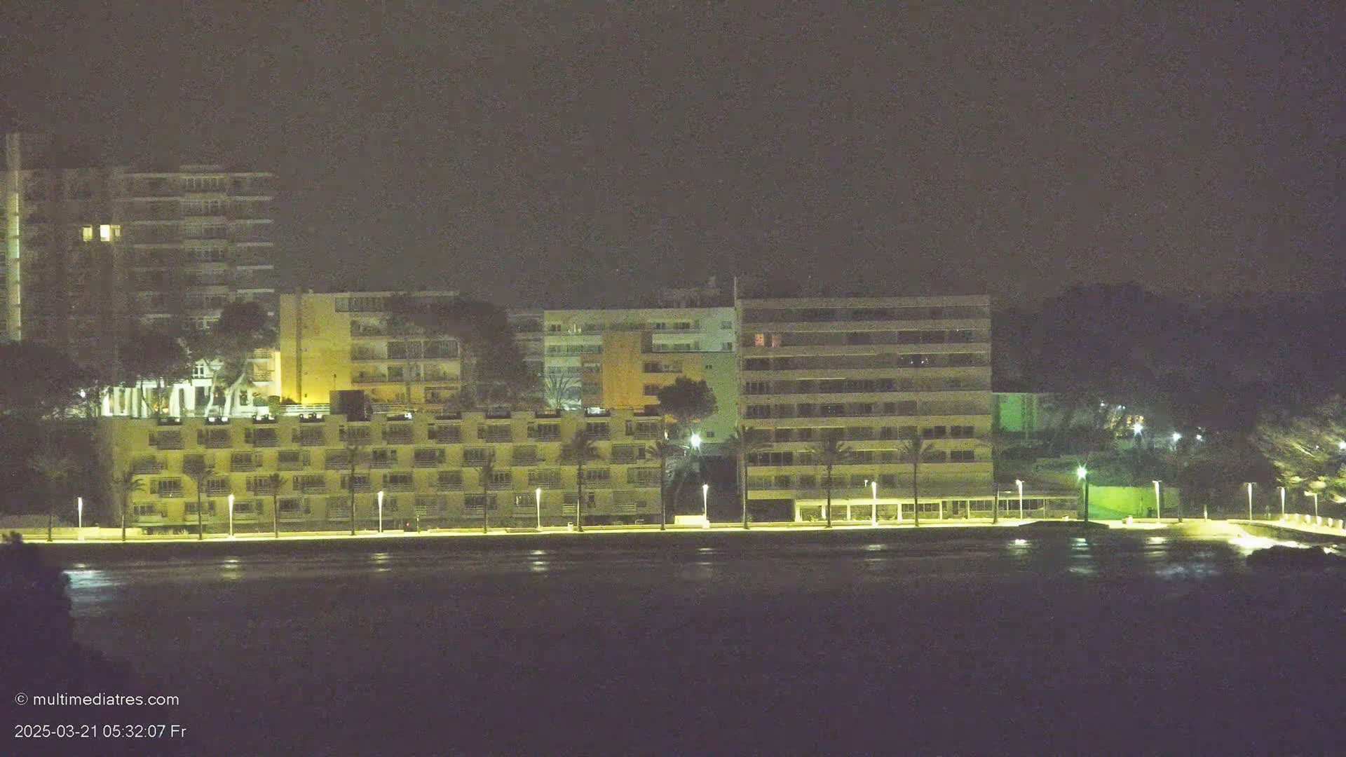 Illuminated apartment buildings line a waterfront at night.
