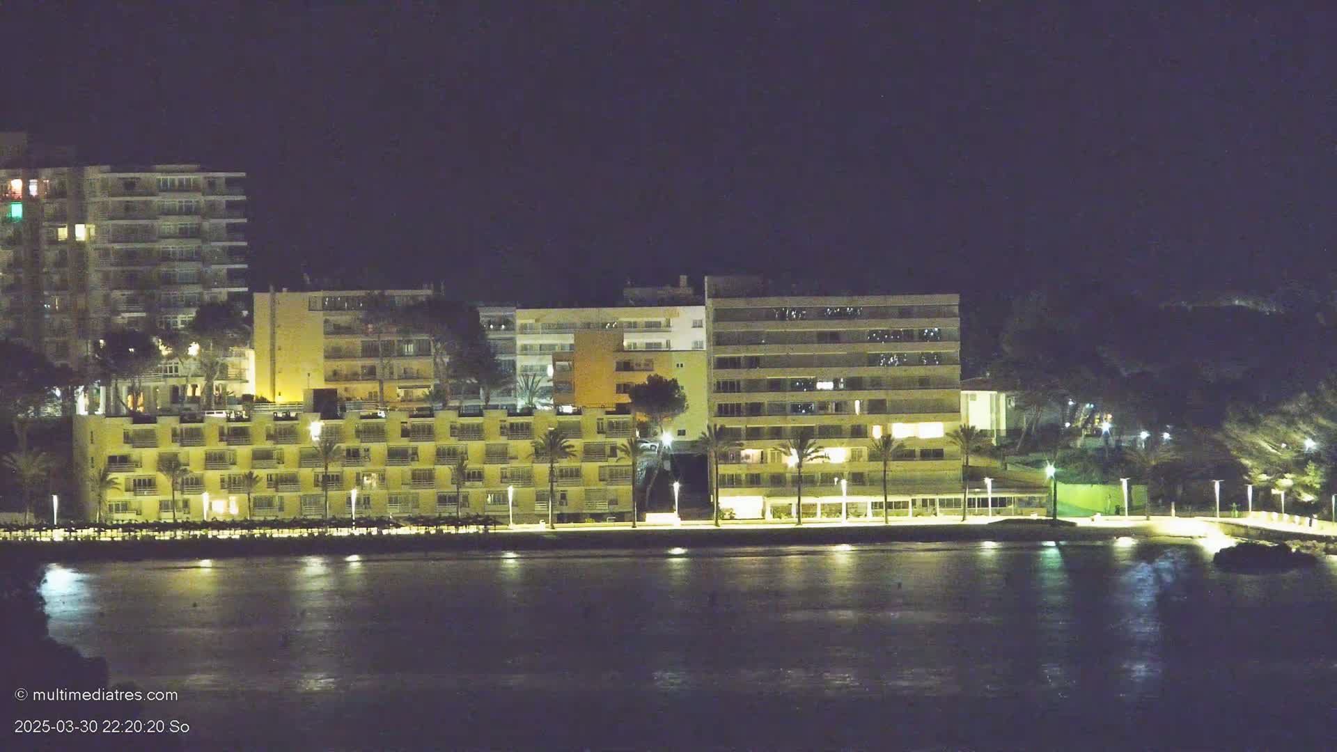 Illuminated buildings line a waterfront at night.