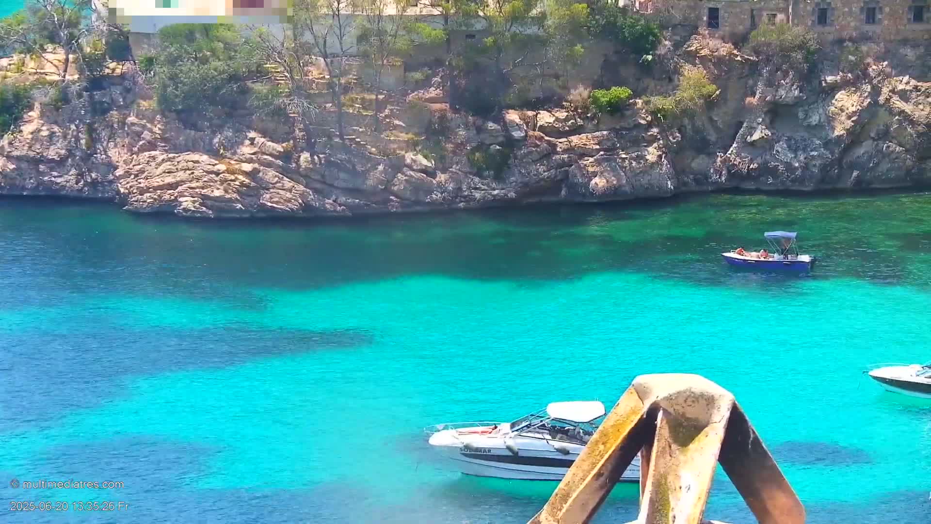 Bright turquoise water surrounds rocky shores with sparse vegetation and two small motorboats are visible.