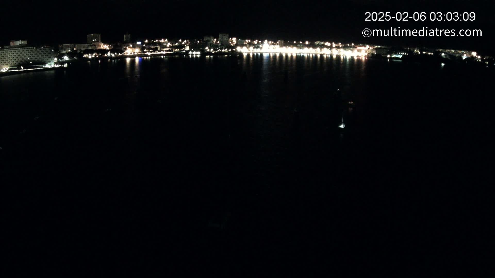 A nighttime view of a city skyline across a dark body of water.