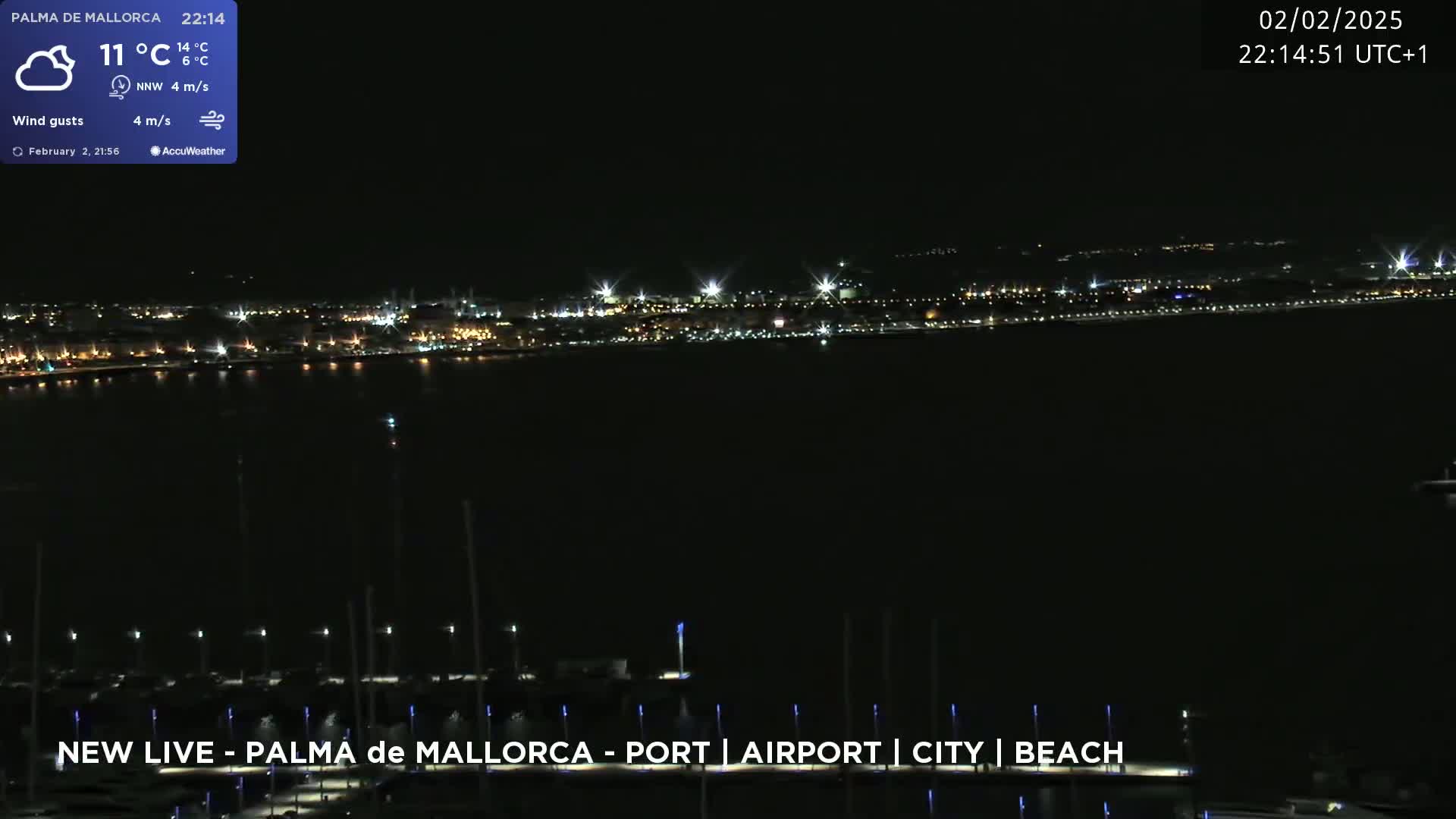 A nighttime view of a city across a body of water, under a mostly clear sky with a light wind.