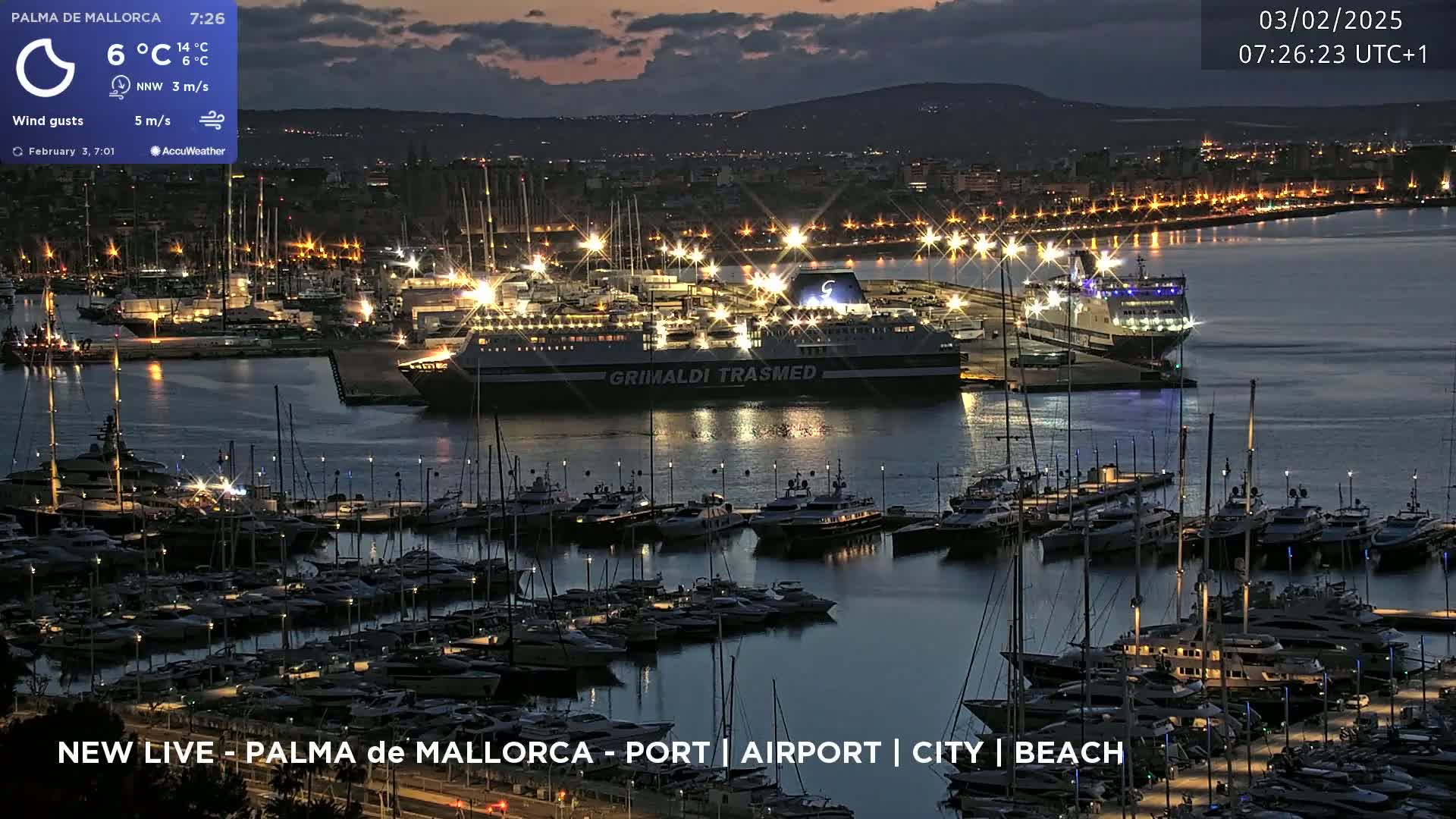 A nighttime harbor scene shows a large ferry docked among numerous smaller boats and yachts, with city lights visible in the background under a twilight sky.