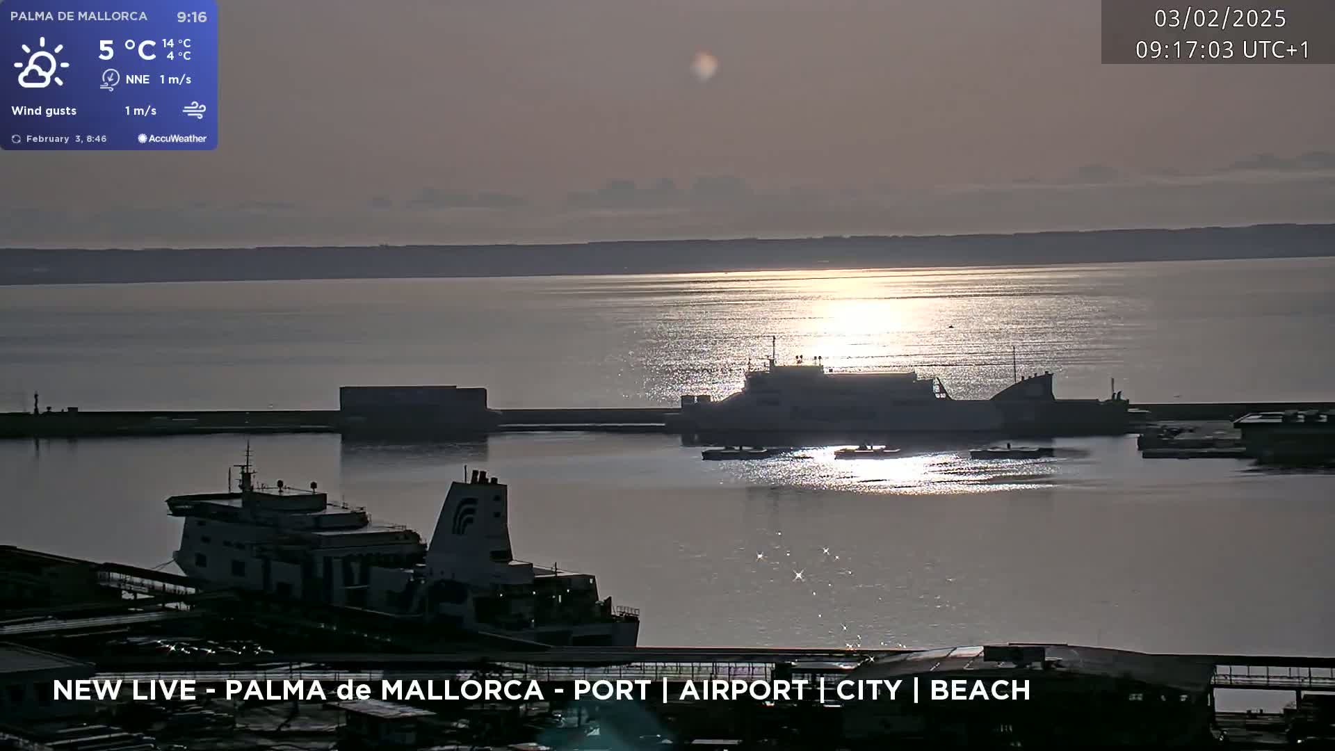 Two ferries are docked at a port on a calm, sunlit body of water under a twilight sky.