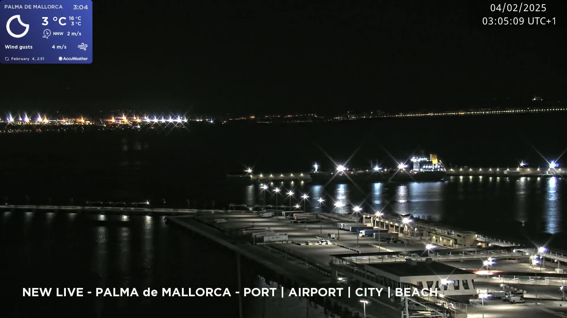 A nighttime view of a port with a ship and several parked vehicles under a clear, dark sky.