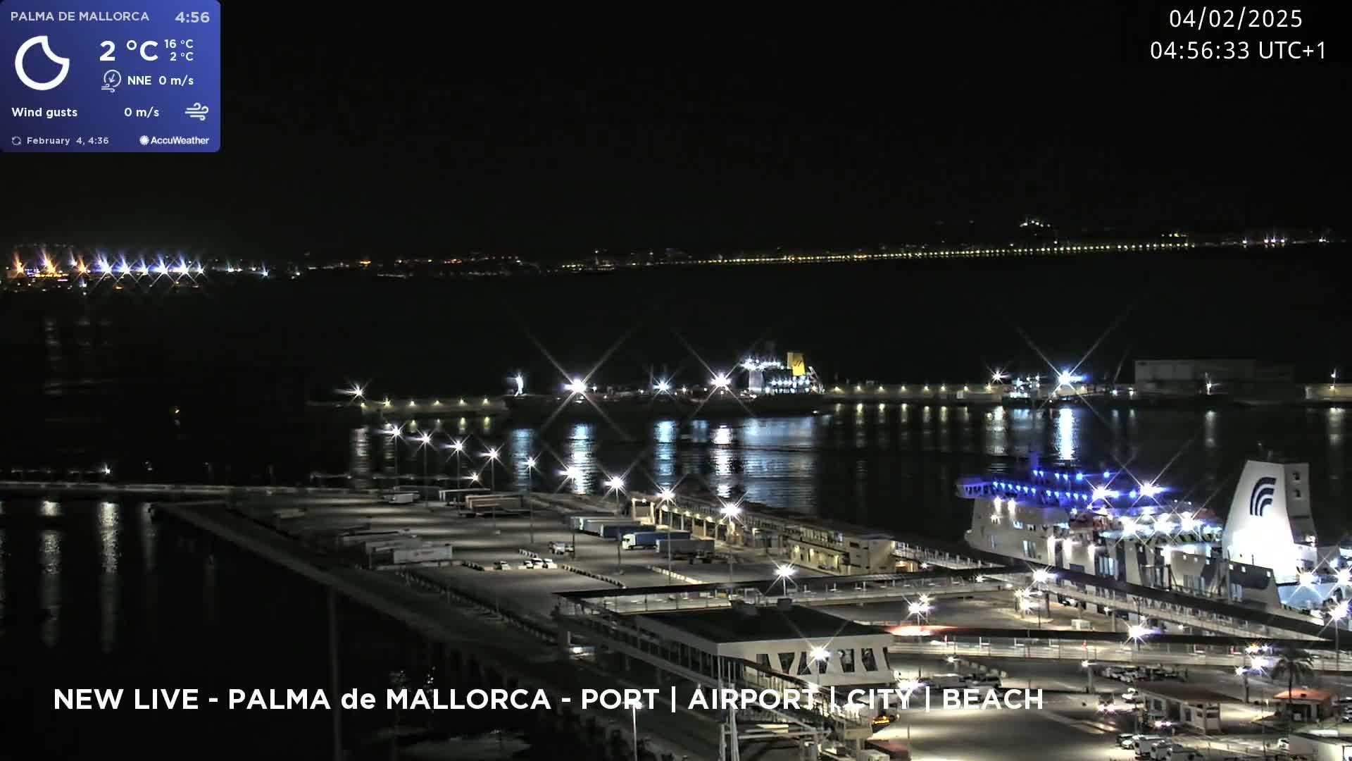 A nighttime, aerial view of a port with a large ferry docked, under a clear, dark sky.