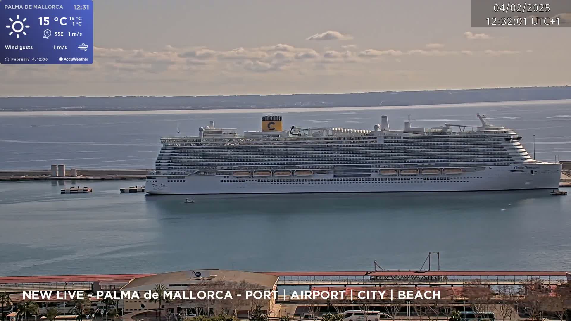 A large cruise ship is docked at a port on a partly cloudy day with a light wind.